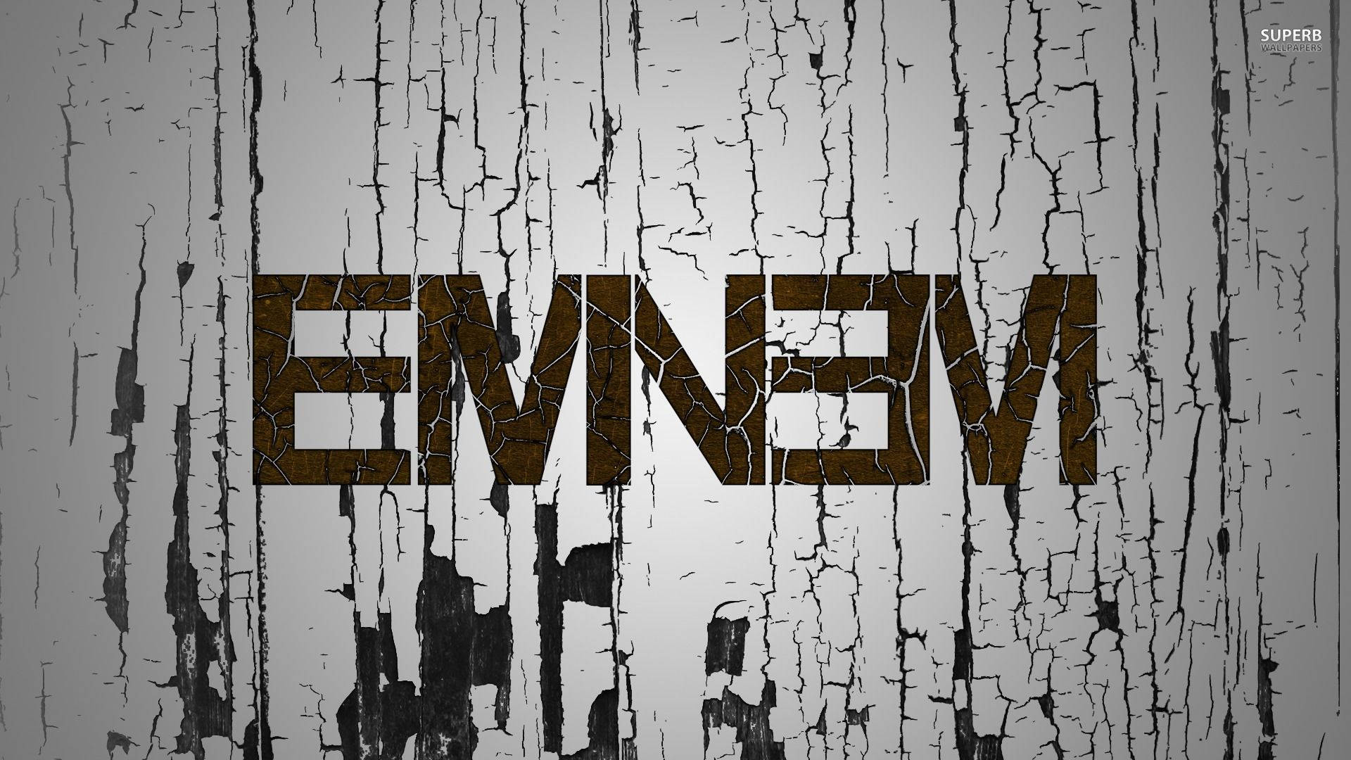 在風化的灰色和黑色木背景上，裂開的棕色字母 'EMNEVM'。
