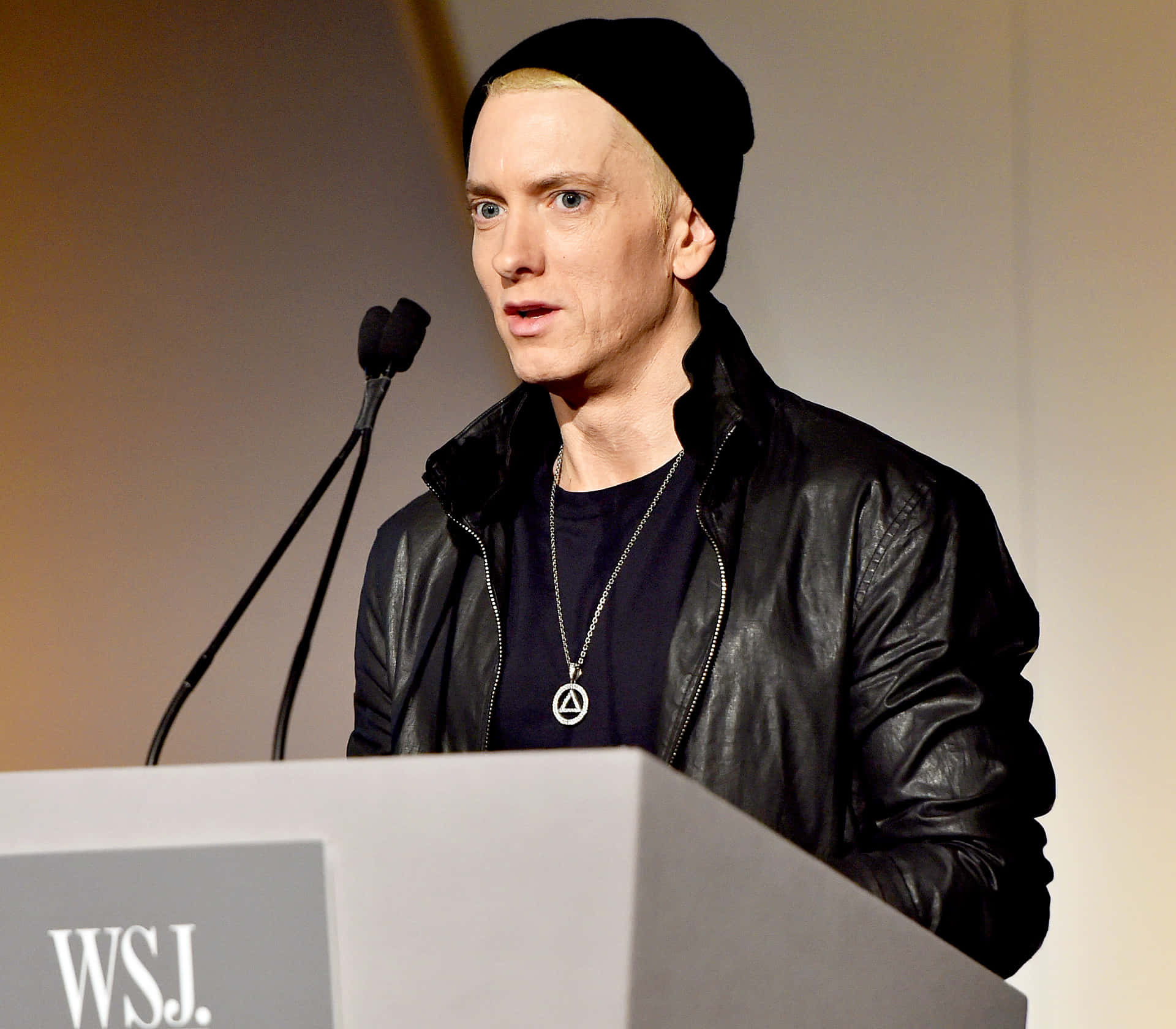 Eminem 桌布 壁紙 — Eminem 站在WSJ講台上，身穿黑色冷帽皮褸和銀色吊墜，對著咪高峰講話。