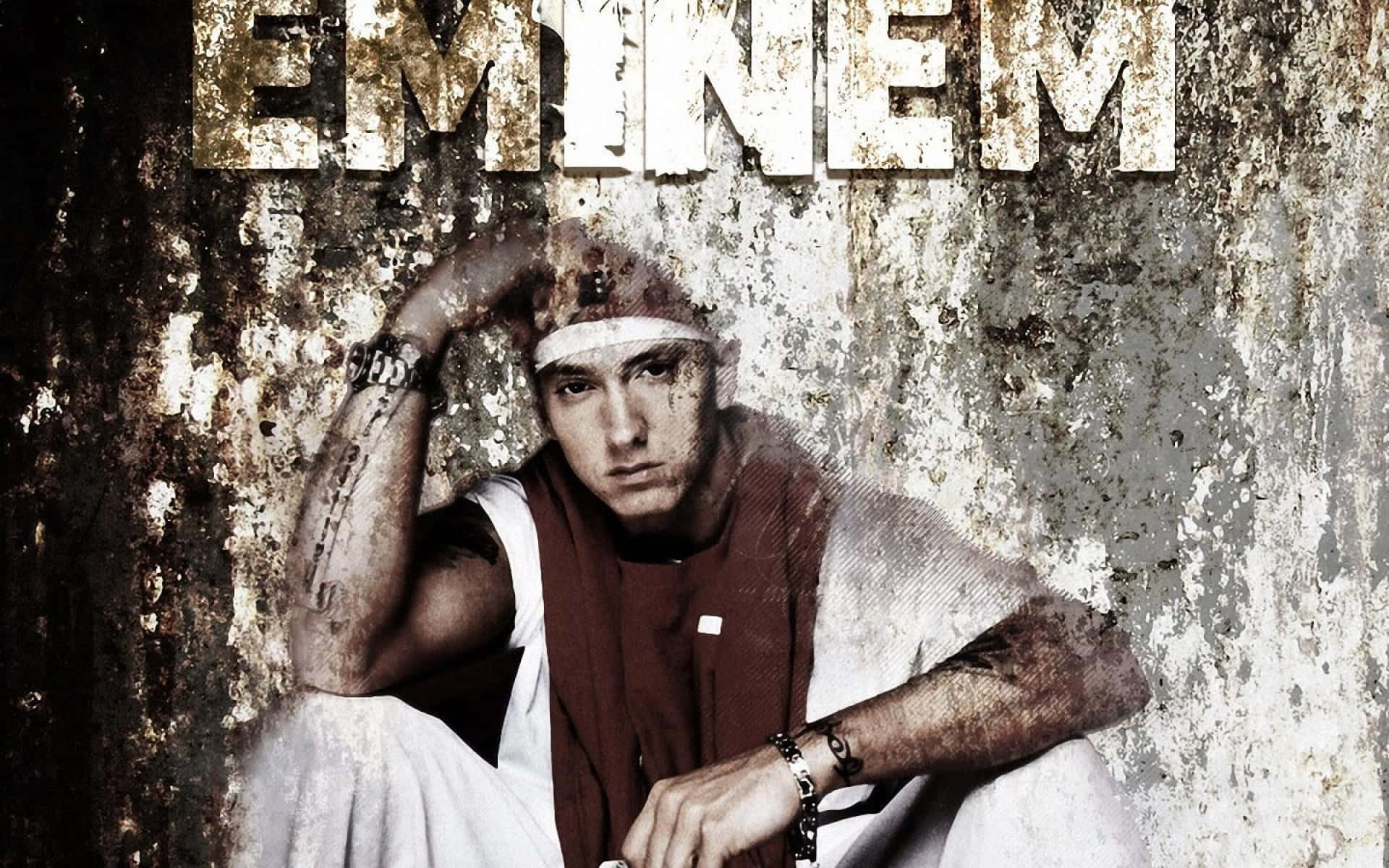 Eminem 桌布 壁紙 — Eminem 靠著一面風化的牆壁坐著，他的名字以粗體顯示在上方，手臂上的紋身清晰可見。