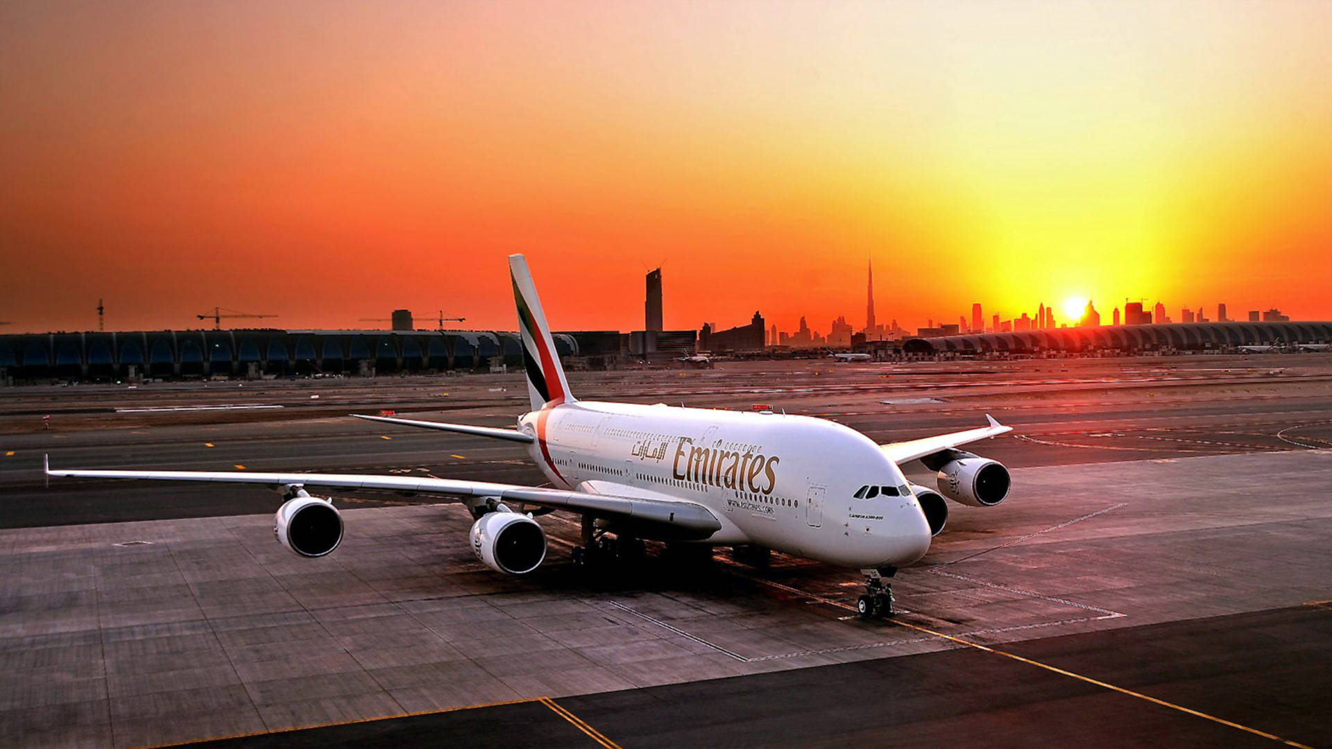 夕陽下，機場停機坪上的阿聯酋航空飛機，背景為城市天際線