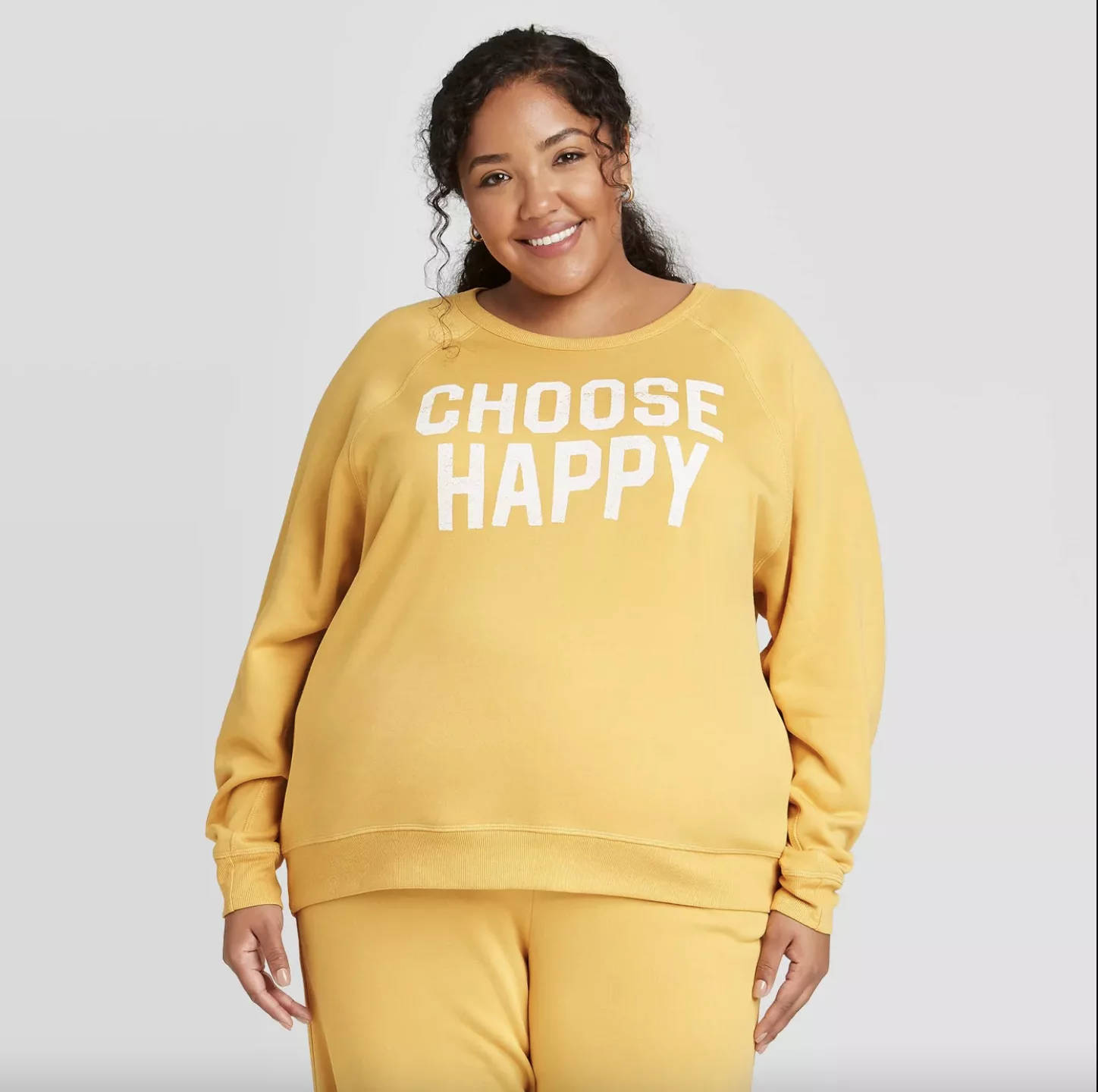 身穿黃色衛衣的女性微笑，帶有 'choose happy' 文字。