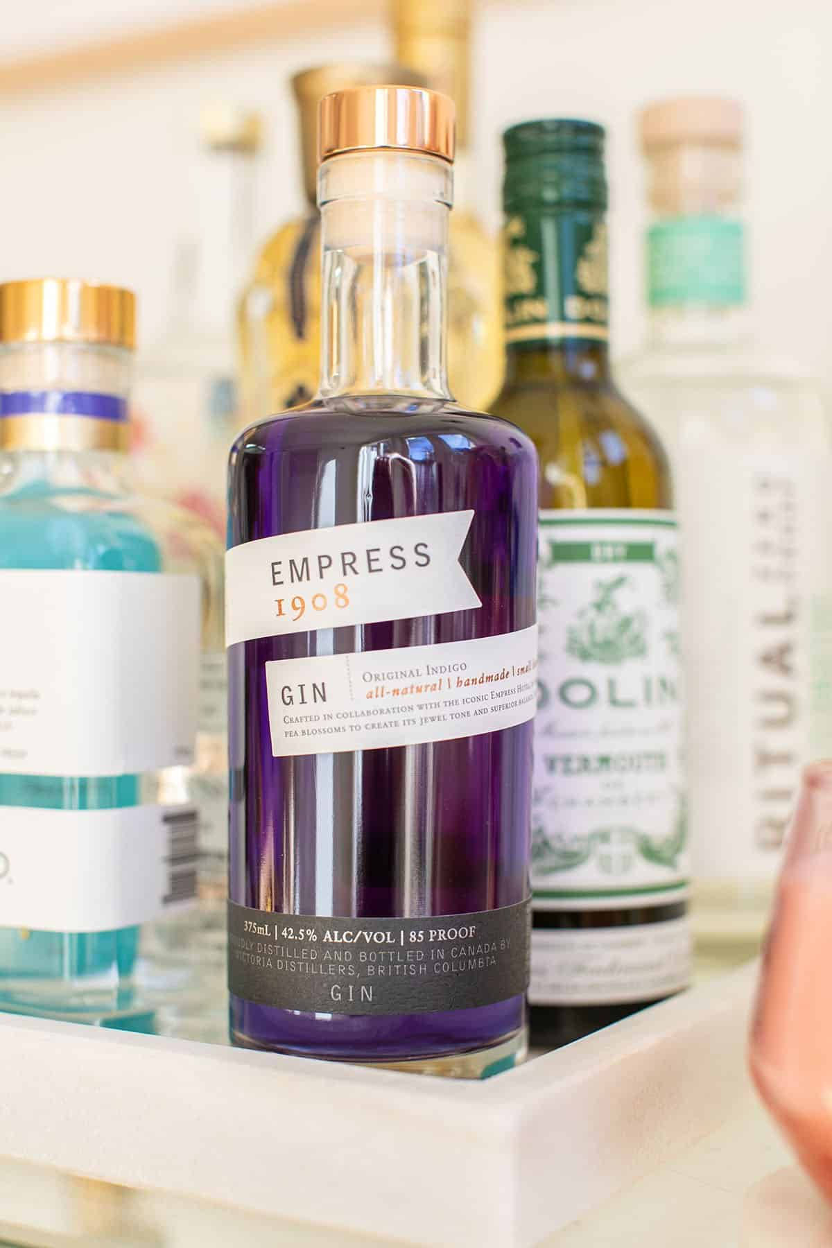 一個帶金色蓋子的紫色氈酒瓶，與其他酒瓶一起放在托盤上。