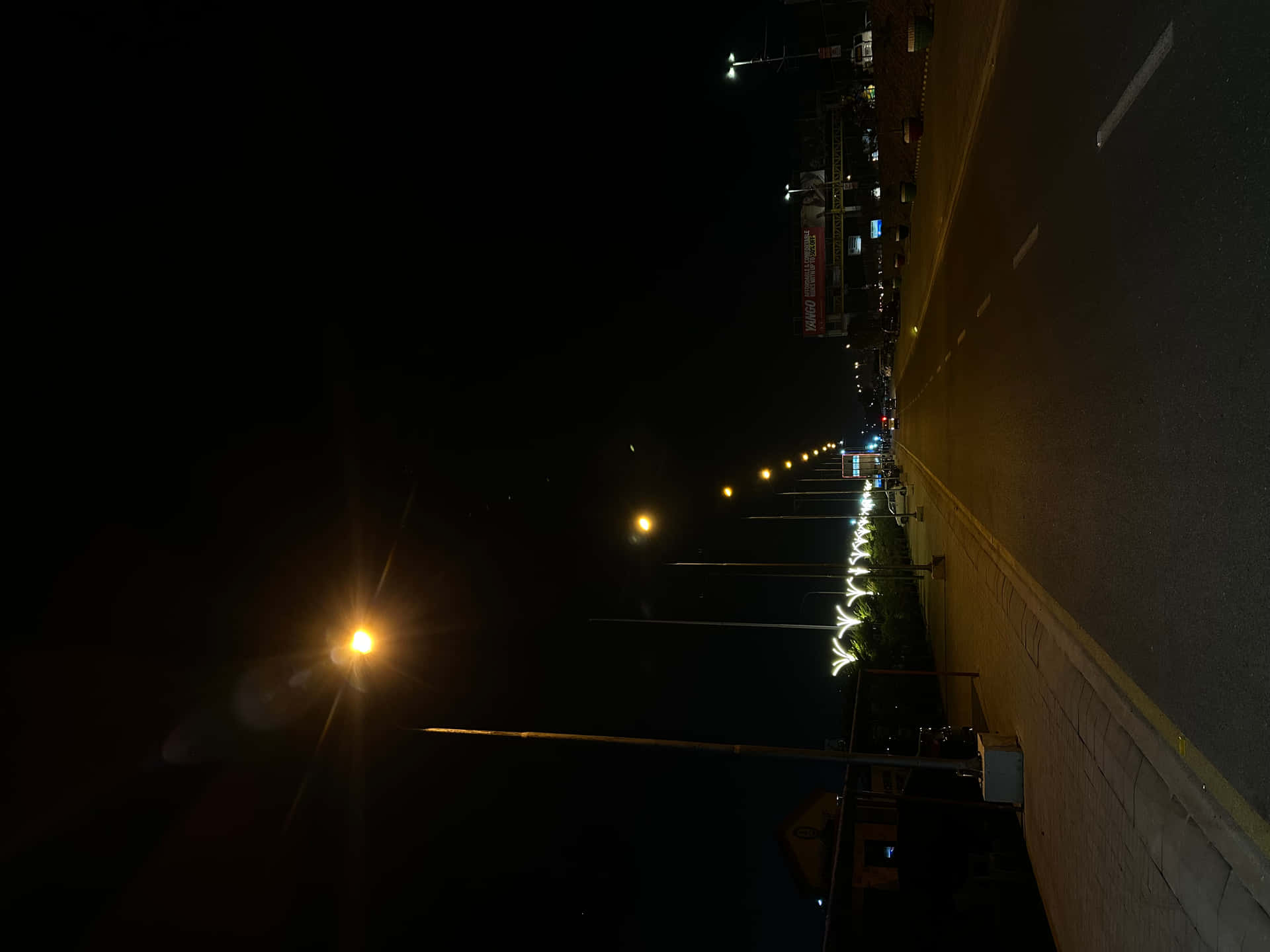 夜晚街道，瀝青道路和人行道上有發光的黃色街燈