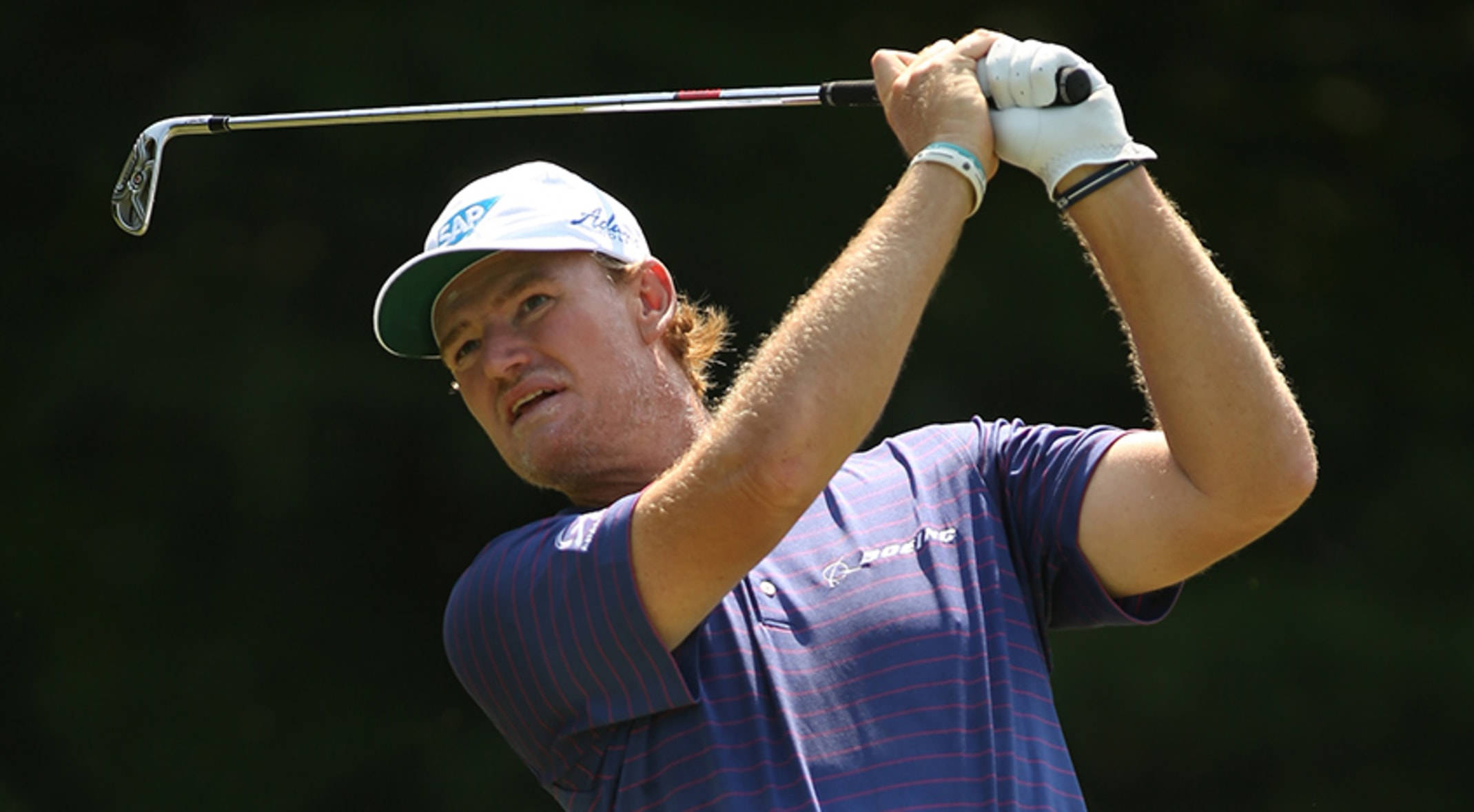 Ernie Els 高爾夫開球後 壁紙 — 一位專注的高爾夫球手在揮桿中途，用一號木桿對著模糊的綠色背景。
