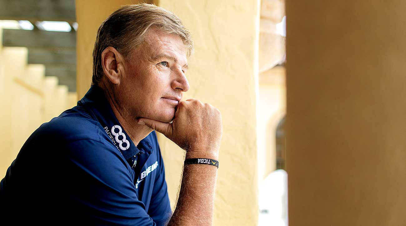 Ernie Els 真實瞬間 壁紙 — 一個沉思中的男人，身穿藍色Polo衫，手托下巴，凝視窗外，溫暖的陽光映照在他的臉上。