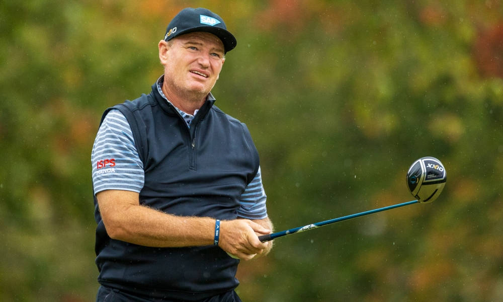 Ernie Els 手持高爾夫球桿 壁紙 — 一名高爾夫球手在模糊的秋葉背景下揮動一號木桿。