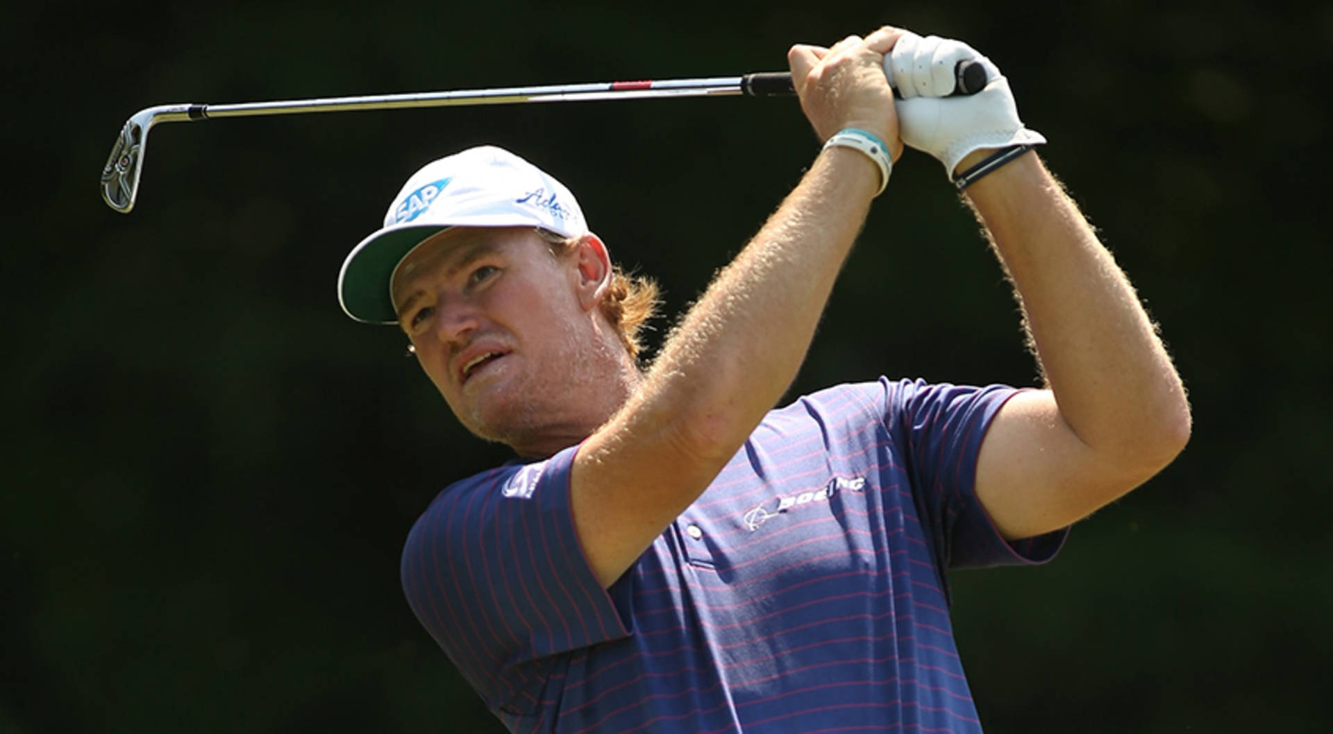 Ernie Els 高爾夫開球後 壁紙 — 一位專注的高爾夫球手在揮桿中途，用一號木桿對著模糊的綠色背景。