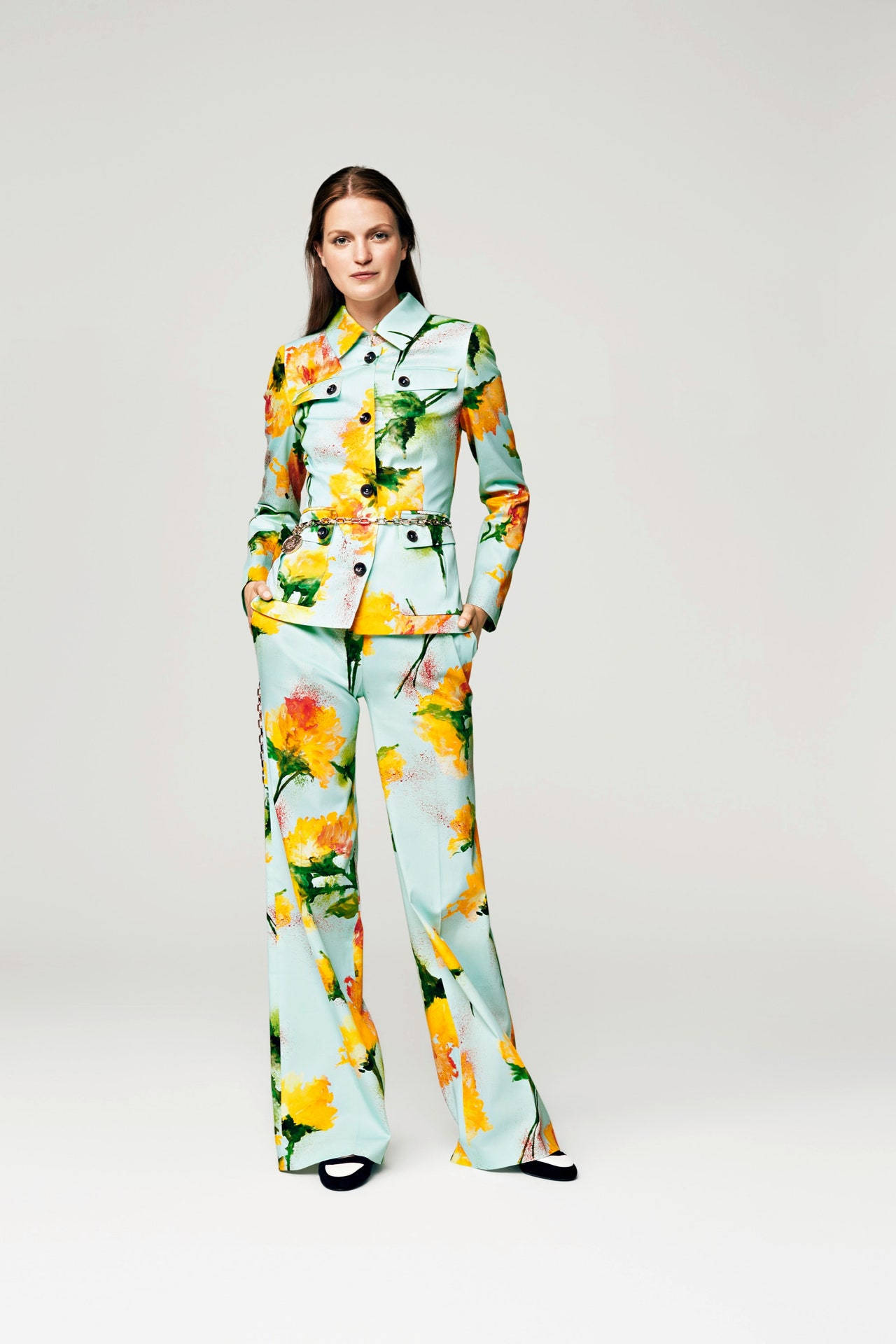 Escada 2016春季系列 壁紙 — 一位女士自信地站在白色背景前，身穿鮮豔的花卉圖案西裝。