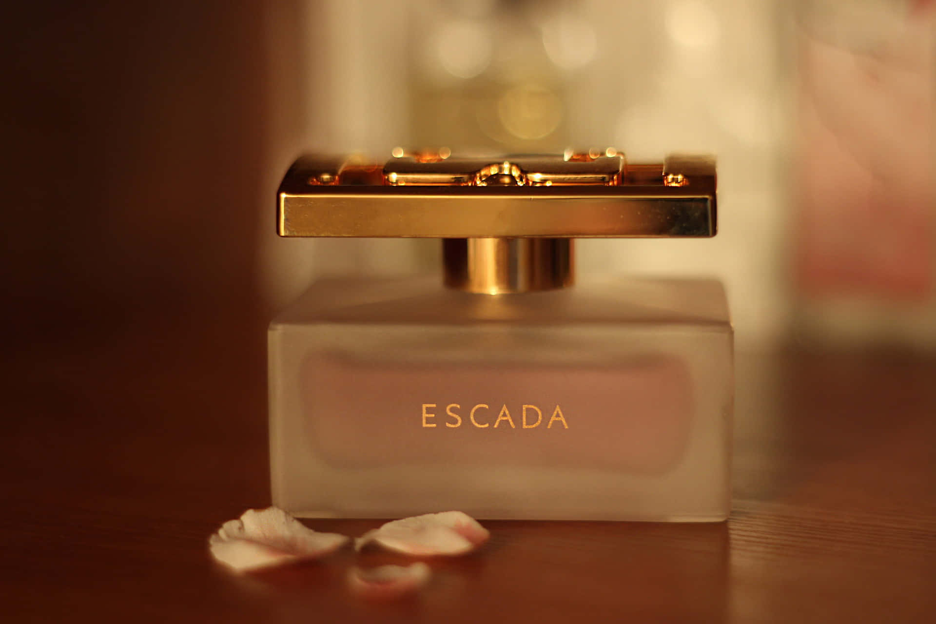 Escada 香水瓶與玫瑰花瓣在木桌上。