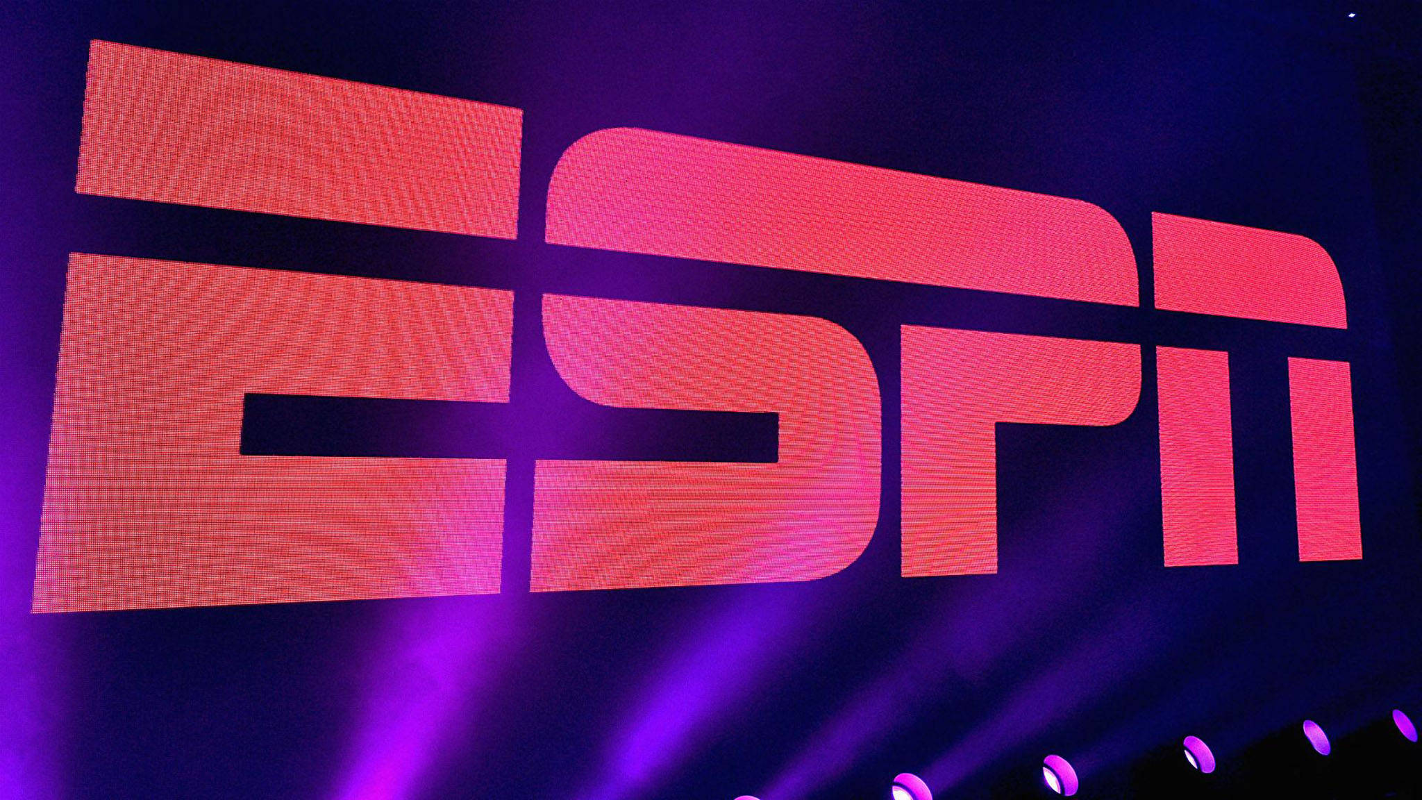 ESPN活動標誌 壁紙 — 在黑暗背景下，紫色舞台燈光照射下，ESPN標誌呈現鮮豔的紅色和粉紅色光芒。