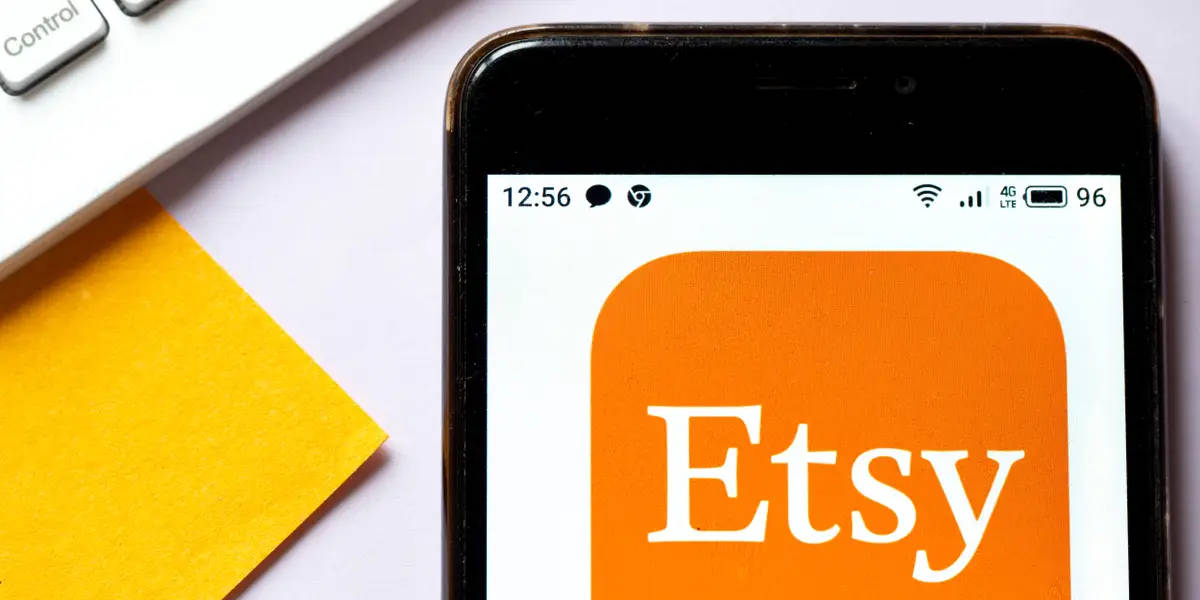 智能手機顯示 Etsy 應用程式，附近有黃色便條紙和鍵盤。
