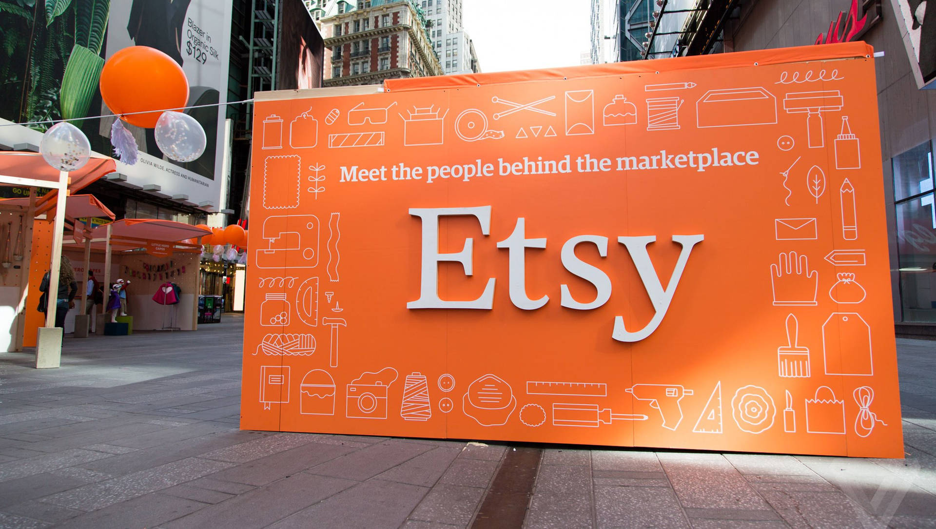 城市廣場上帶有白色圖標的大型橙色Etsy標誌，伴有氣球。