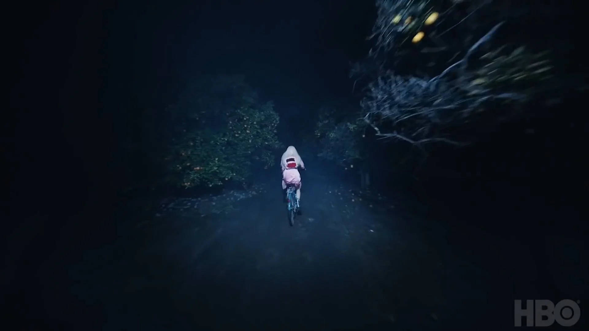 小孩在夜晚騎自行車穿過黑暗森林，伴有發光球體