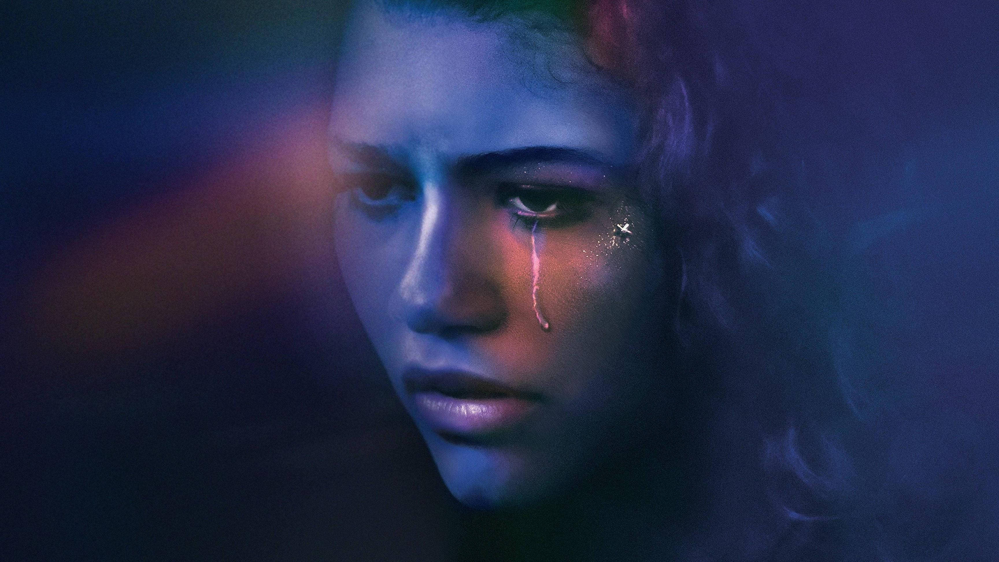 Euphoria Rue特寫 壁紙 — 一個女人的特寫肖像，淚水在霓虹藍和紫色燈光下順著臉頰流下。