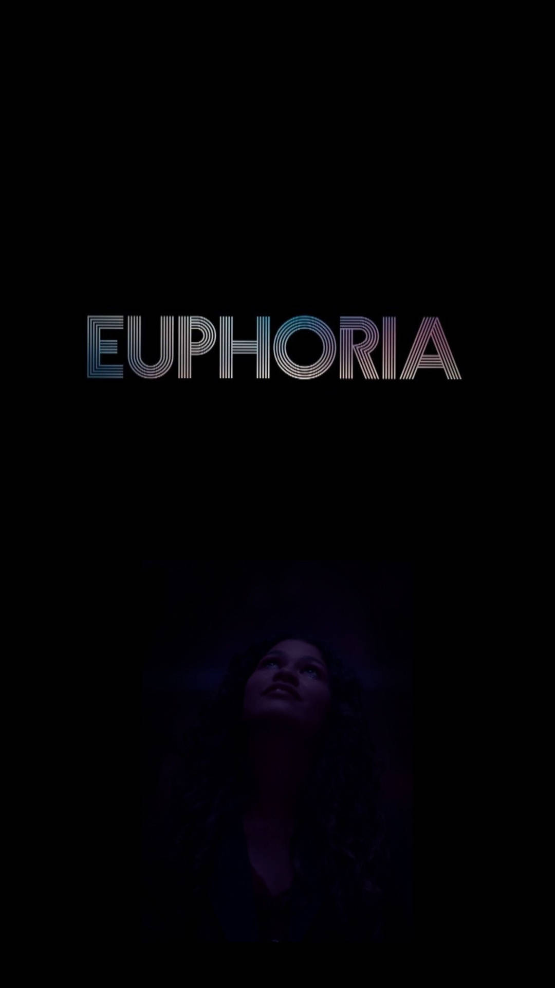 女性在黑暗中於發光的EUPHORIA文字下向上看。