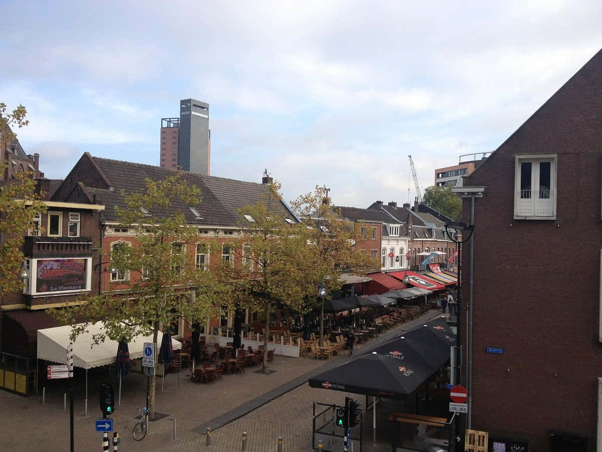 Tilburg 桌布 壁紙 — 一個歐洲城市廣場，有磚砌建築、戶外咖啡館，以及一座在陰天可見的高層現代塔樓。