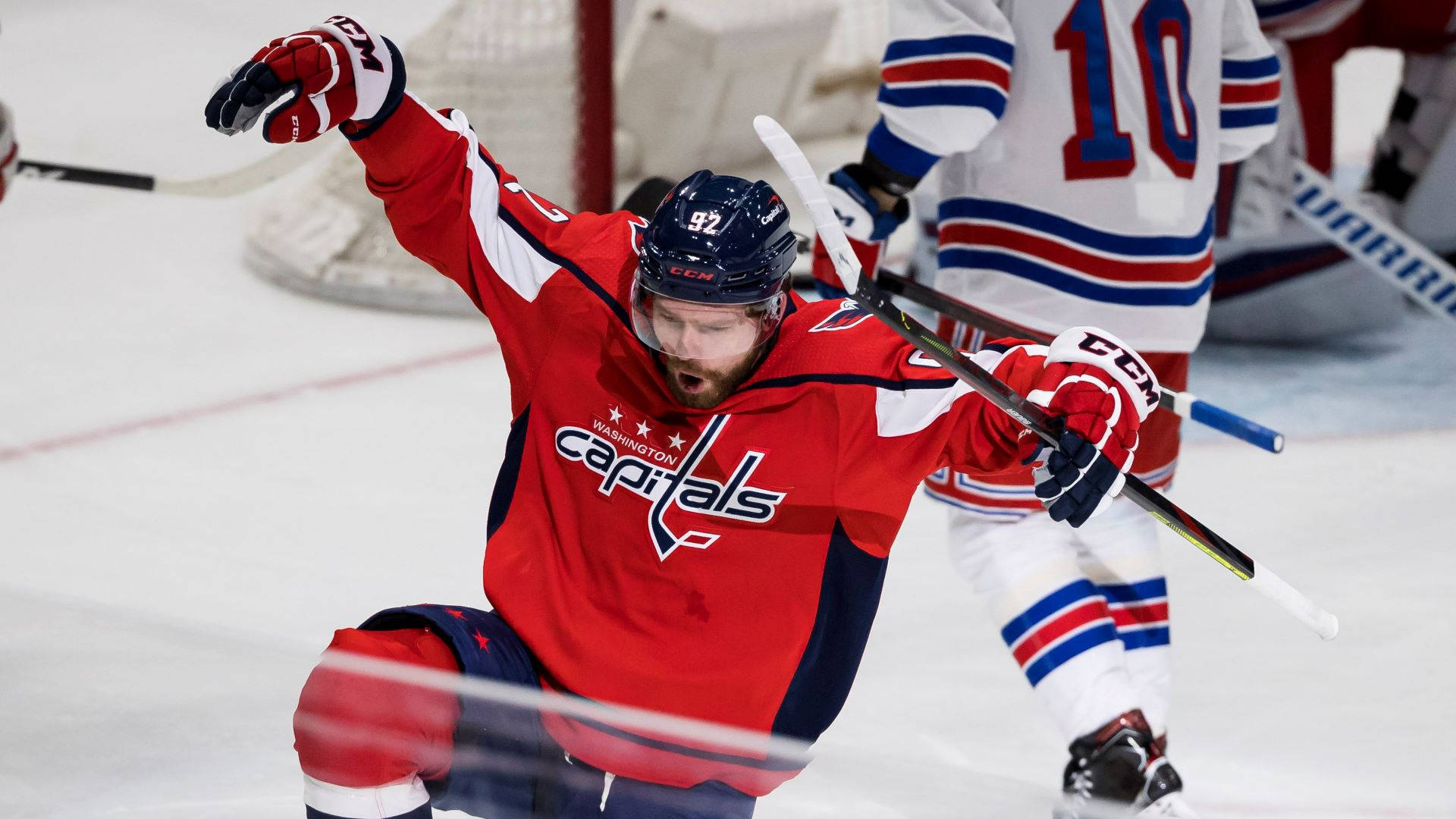 Evgeny Kuznetsov 防守動作 壁紙 — 一名身穿紅色球衣的華盛頓首都隊冰球運動員在冰上高舉雙臂慶祝入球。