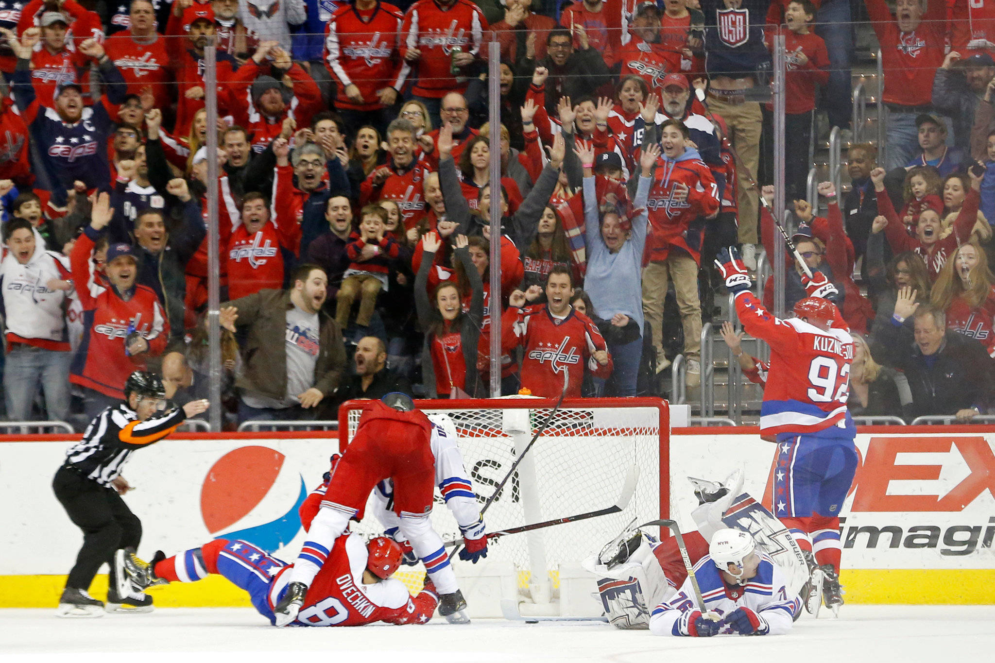 Evgeny Kuznetsov 與隊友慶祝勝利 壁紙 — 冰球球員慶祝入球，紅色衣著的球迷在玻璃後瘋狂歡呼。