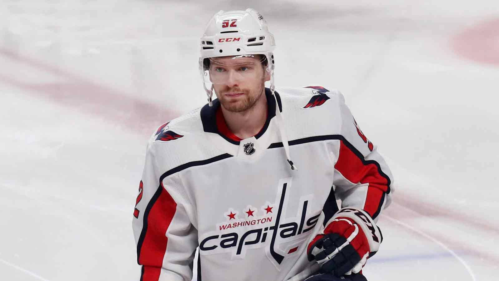 Evgeny Kuznetsov 穿著白色戰袍 壁紙 — 一位專注的華盛頓首都隊冰球運動員穿著白色紅色和黑色制服在冰場上怒目而視。