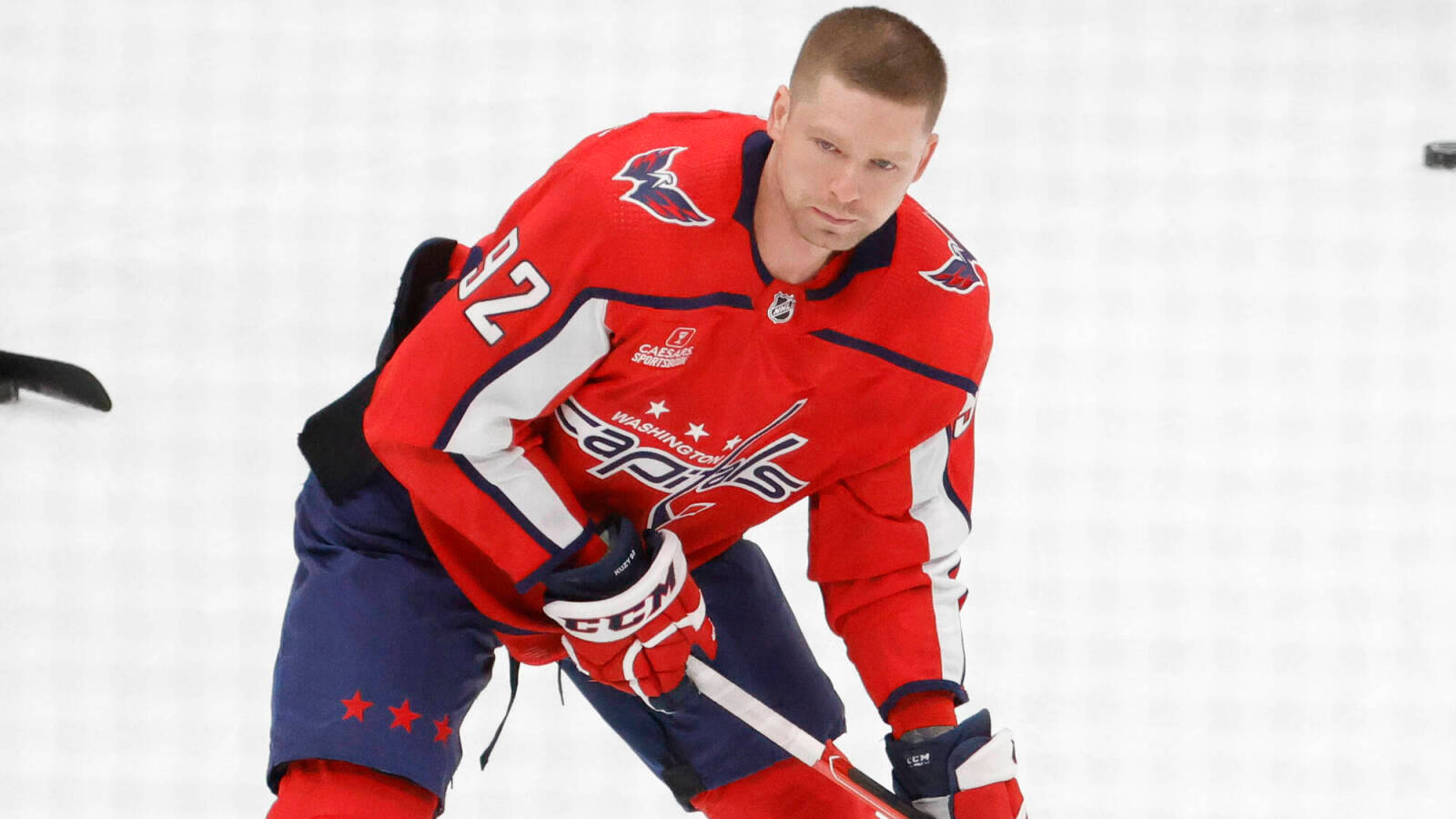 Evgeny Kuznetsov 場上精彩表現 壁紙 — 一位專注的華盛頓首都隊冰球運動員身穿紅色球衣，低蹲在冰上，手持球桿。