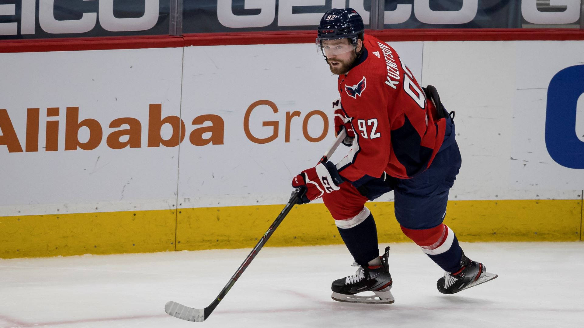 Evgeny Kuznetsov 冰球運動員 壁紙 — 一名身穿紅色92號球衣的冰球運動員在比賽中專注地滑行在冰面上。