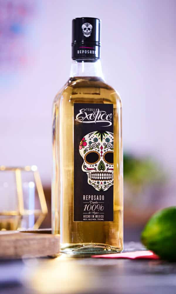 糖骷髏設計的龍舌蘭酒瓶，旁邊有青檸和金色玻璃杯。