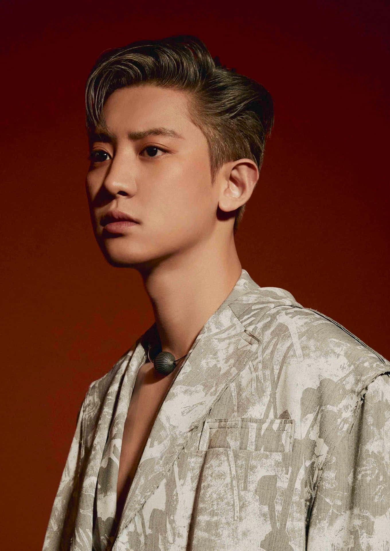 EXO震撼現場演出 壁紙 — 一位年輕男子梳著時尚髮型，穿著圖案襯衫，在戲劇性的工作室燈光下，背景是濃郁的紅色。
