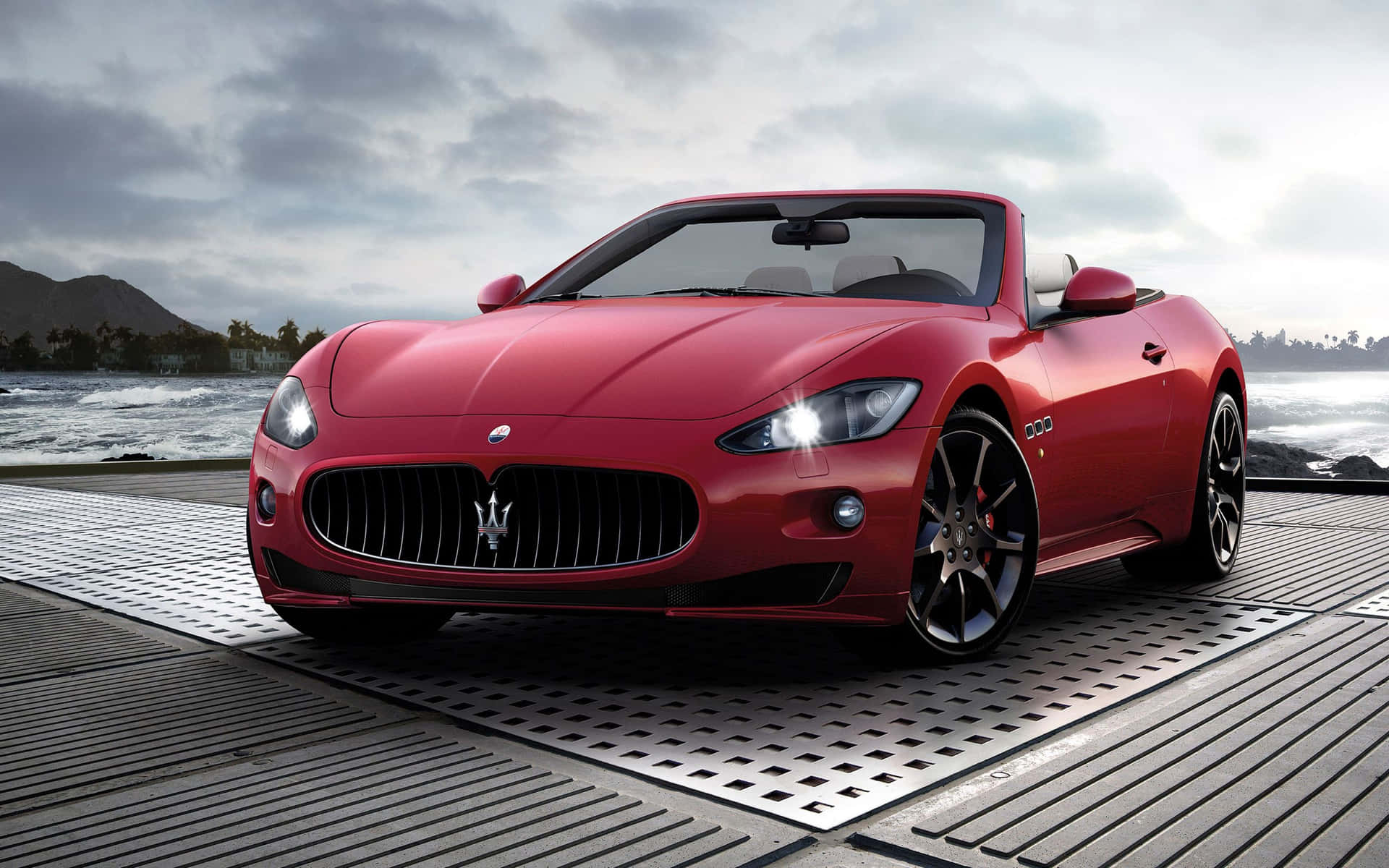 紅色Maserati開篷車停在海邊金屬碼頭，海浪拍打。