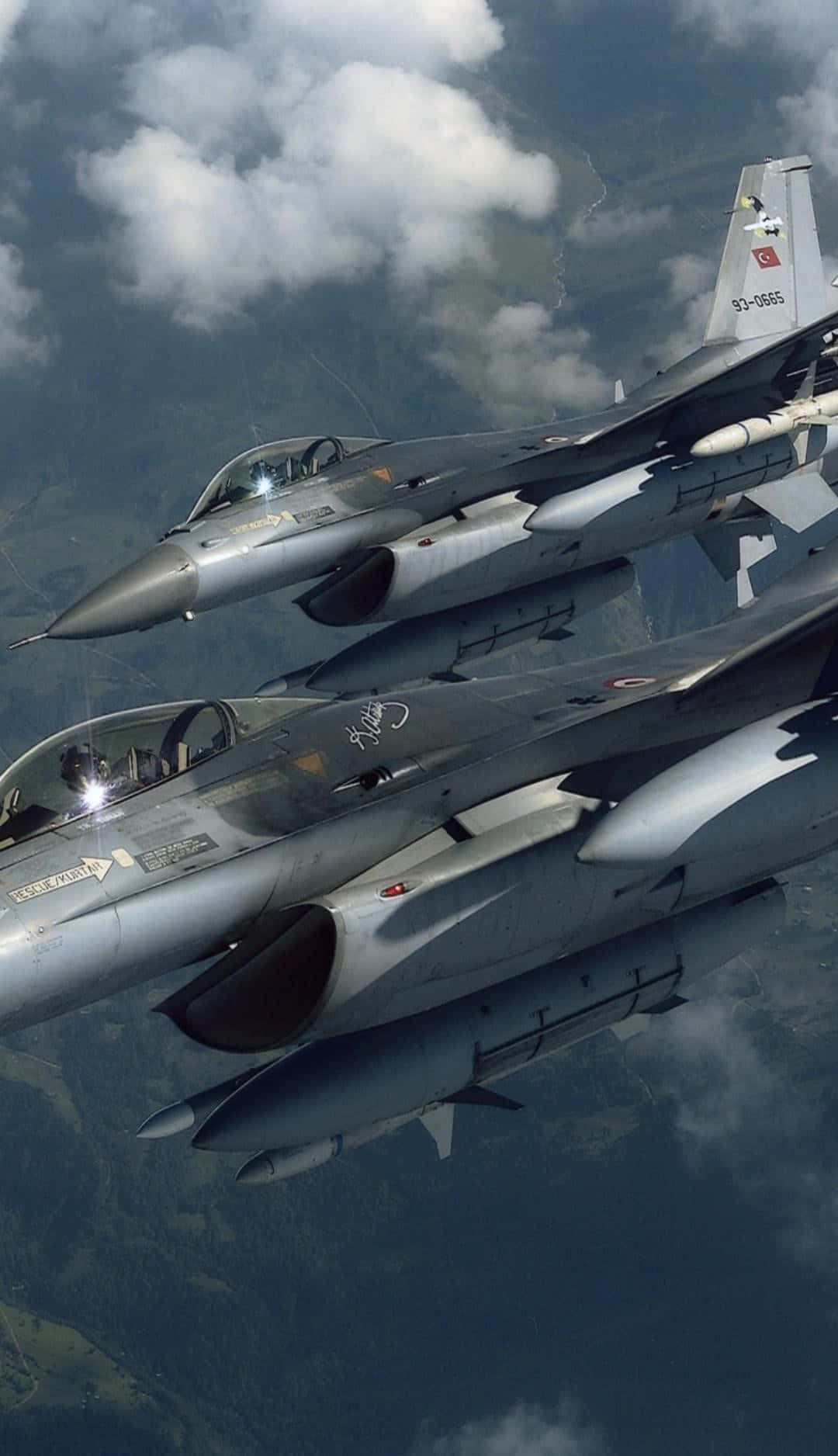 F-16戰隼飛行Android巨型飛機背景 壁紙 — 兩架戰鬥機以編隊飛行於雲朵點綴的景觀之上，可見駕駛艙細節及安裝的導彈。