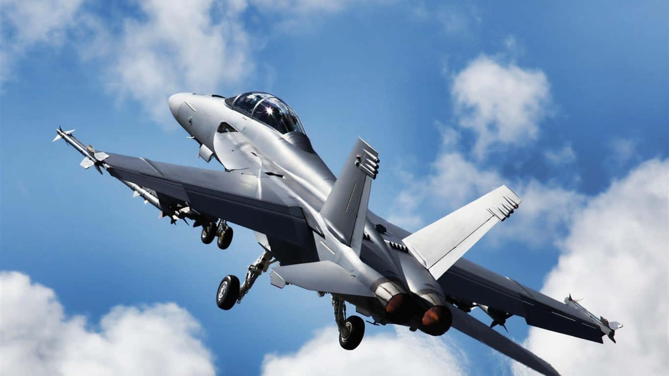 F-18 向上飛行於雲層中的巨型客機背景（1366x768） 壁紙 — 一架流線型銀色戰鬥機在點綴著蓬鬆白雲的明亮藍天中向上攀升。