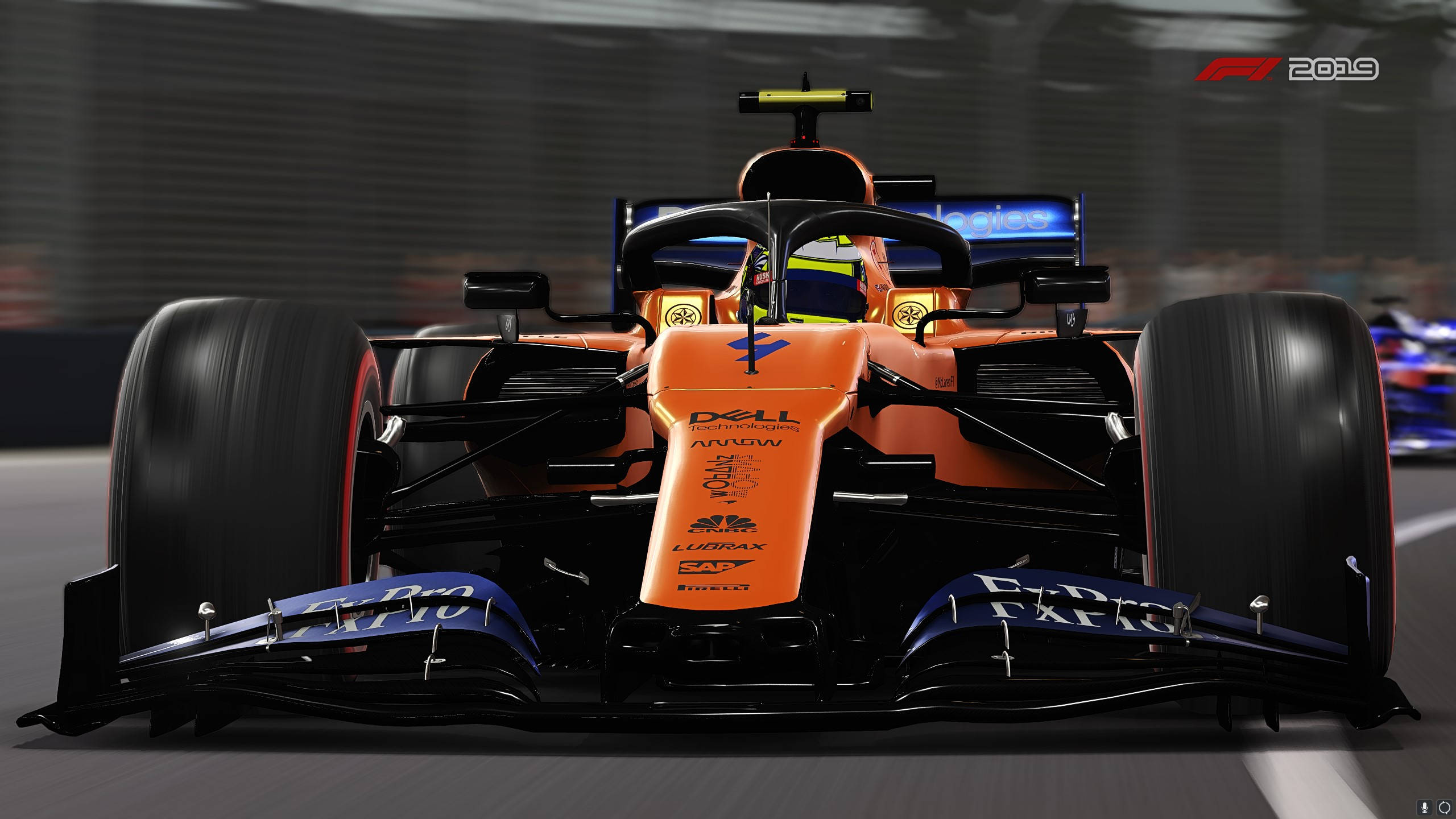 F1 2019 賽車近距離特寫 壁紙 — 一輛充滿活力的橙色和黑色一級方程式賽車在賽道上疾馳，帶有模糊的動感和可見的贊助商標誌。