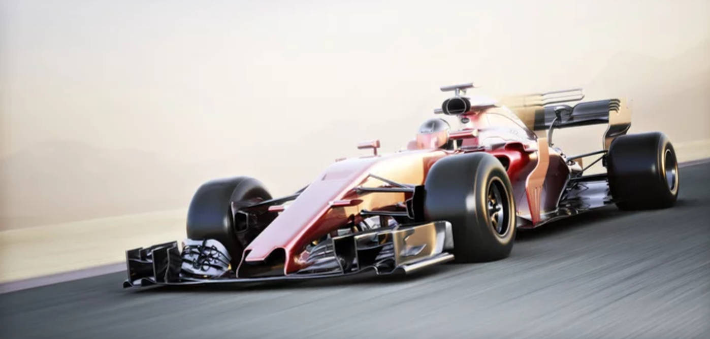 高速行駛的F1 4K賽車 壁紙 — 一輛紅金色一級方程式賽車在模糊的賽道上於朦朧的日光下疾馳。