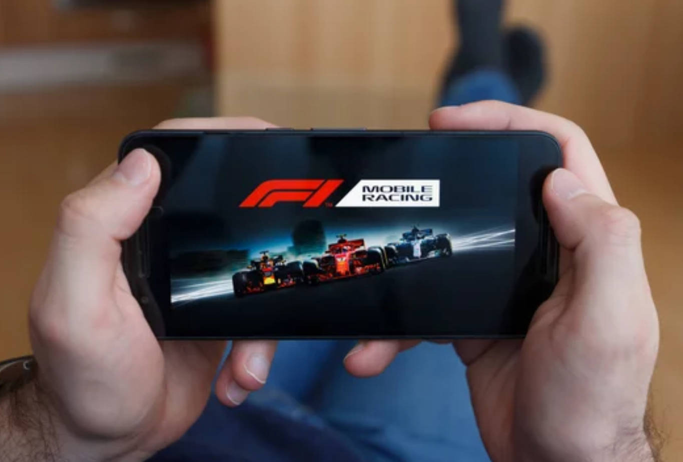 人拿著手機玩F1 Mobile Racing遊戲，屏幕上顯示賽車。