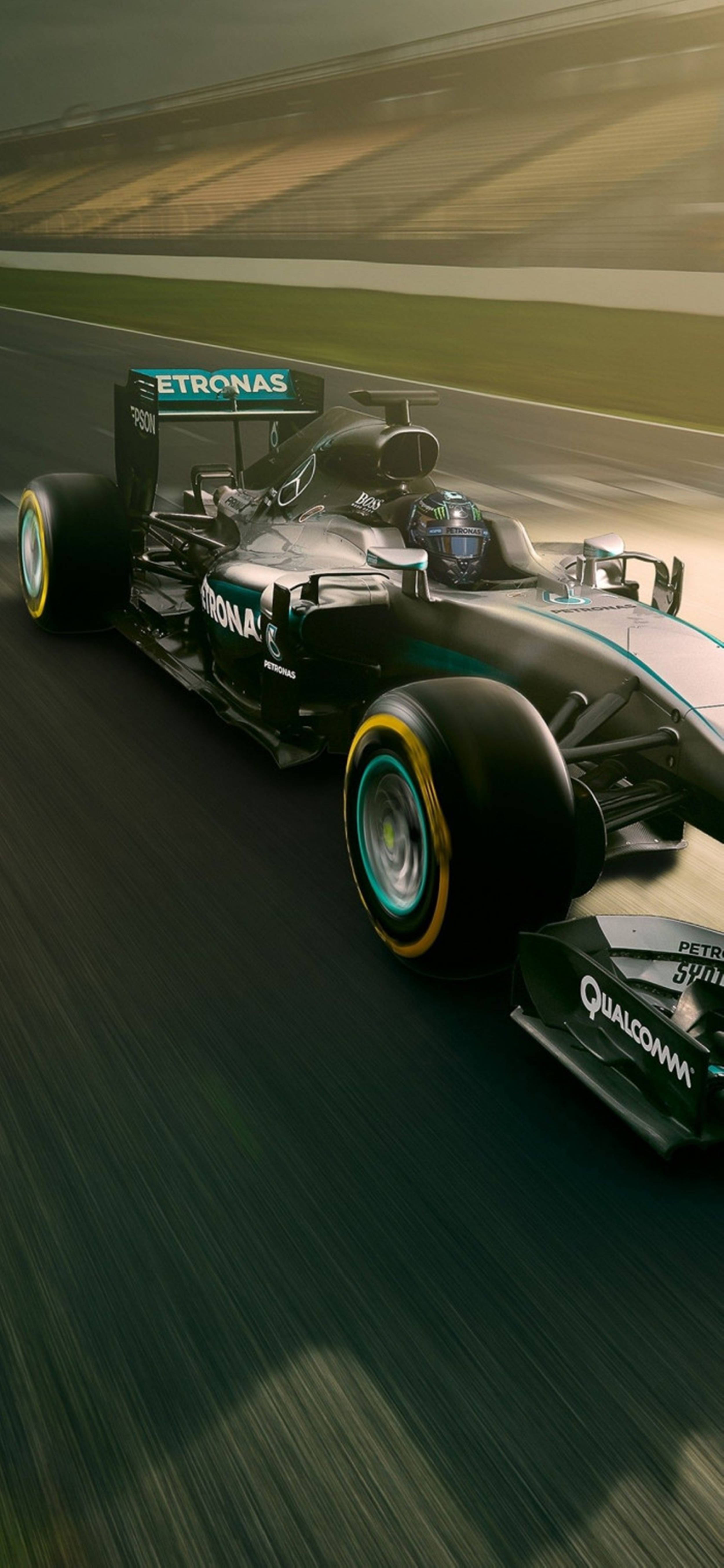 F1手機黑色梅賽德斯賽車 壁紙 — 一架時尚的黑色和藍綠色一級方程式賽車沿著賽道疾馳，動態模糊傳達出高速感。