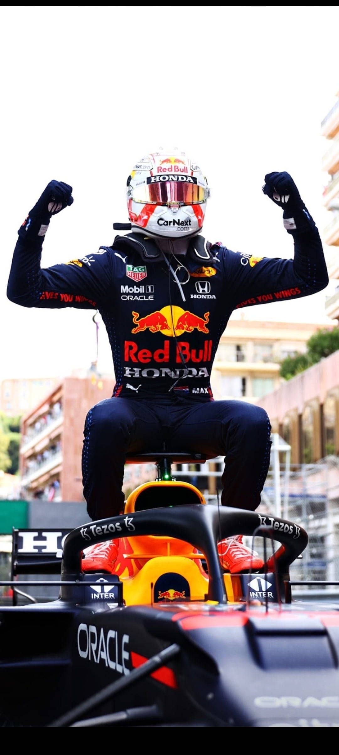 F1 麥克·維斯塔潘蒙特卡洛大獎賽勝利 iPhone 壁紙 — 一名身穿紅牛賽車服的F1車手在賽車頂上高舉拳頭慶祝勝利。