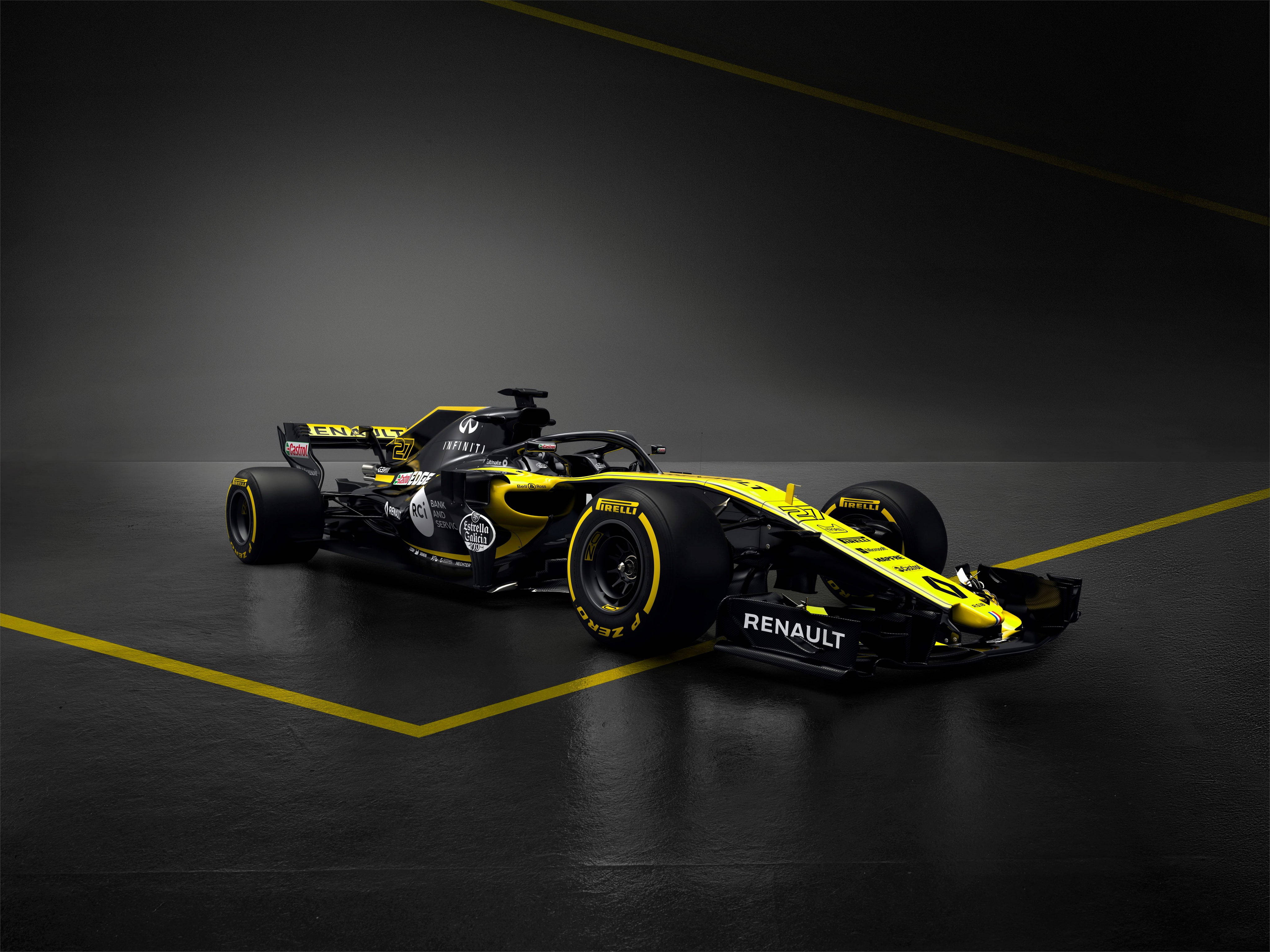 雷諾 F1 賽車 RS18 壁紙 — 一輛流線型的雷諾一級方程式賽車，採用鮮黃色和黑色，停在深色地板上，地板上有大膽的黃色線條，在戲劇性的攝影棚燈光下。
