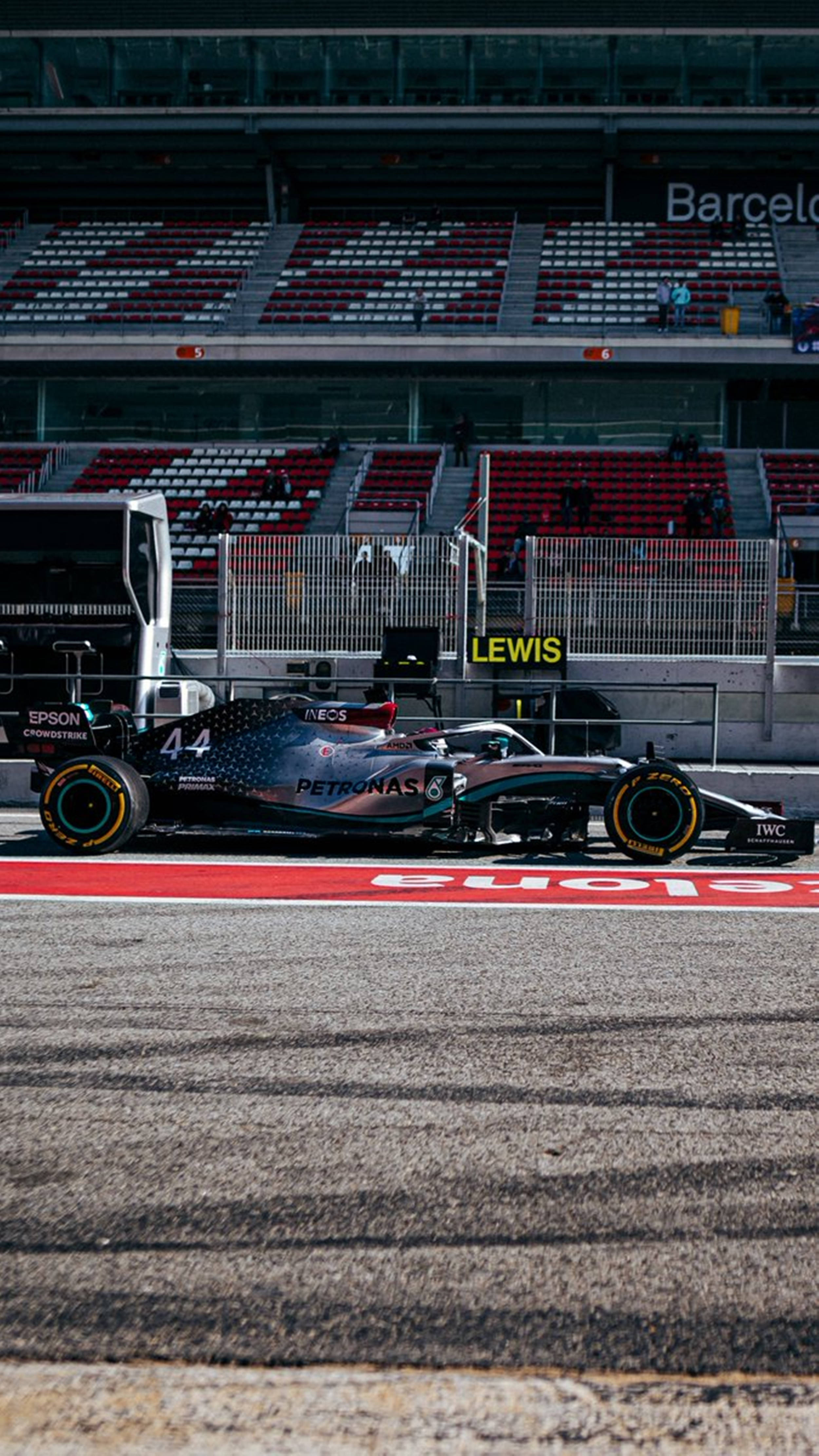 F1手機梅賽德斯漢密爾頓 壁紙 — 一架時尚的銀黑色一級方程式賽車，車號44，停在巴塞隆納的賽道上，背景是紅色的看台。