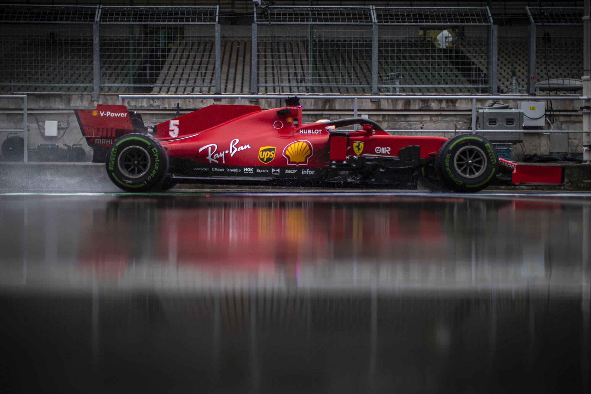 F1 費拉利維特爾賽車 壁紙 — 一輛紅色法拉利一級方程式賽車，編號5，在潮濕的賽道上疾馳，反射出其鮮豔的塗裝。