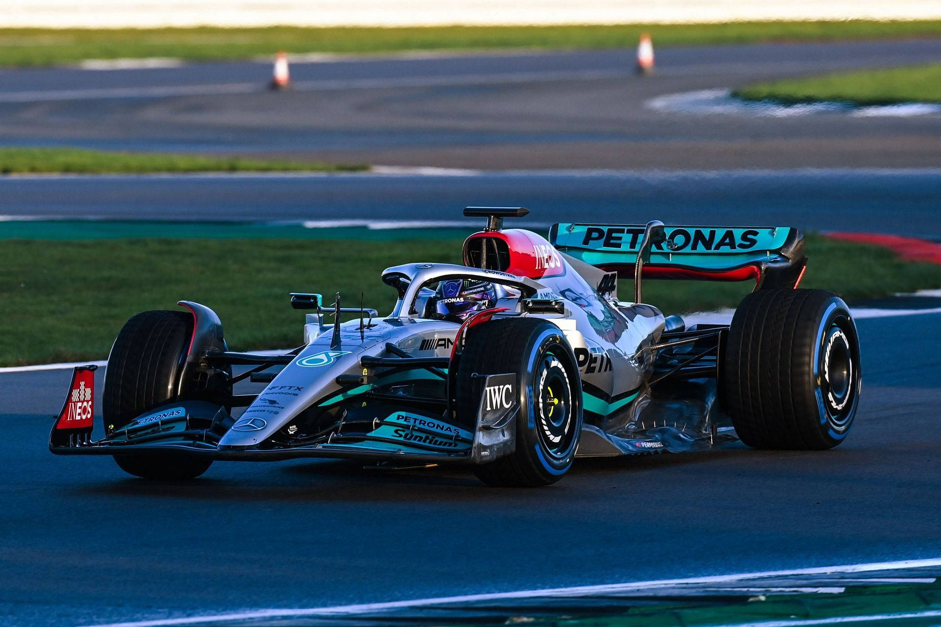 一級方程式賽車在黃昏時分於賽道上高速行駛，帶有Petronas品牌標誌。