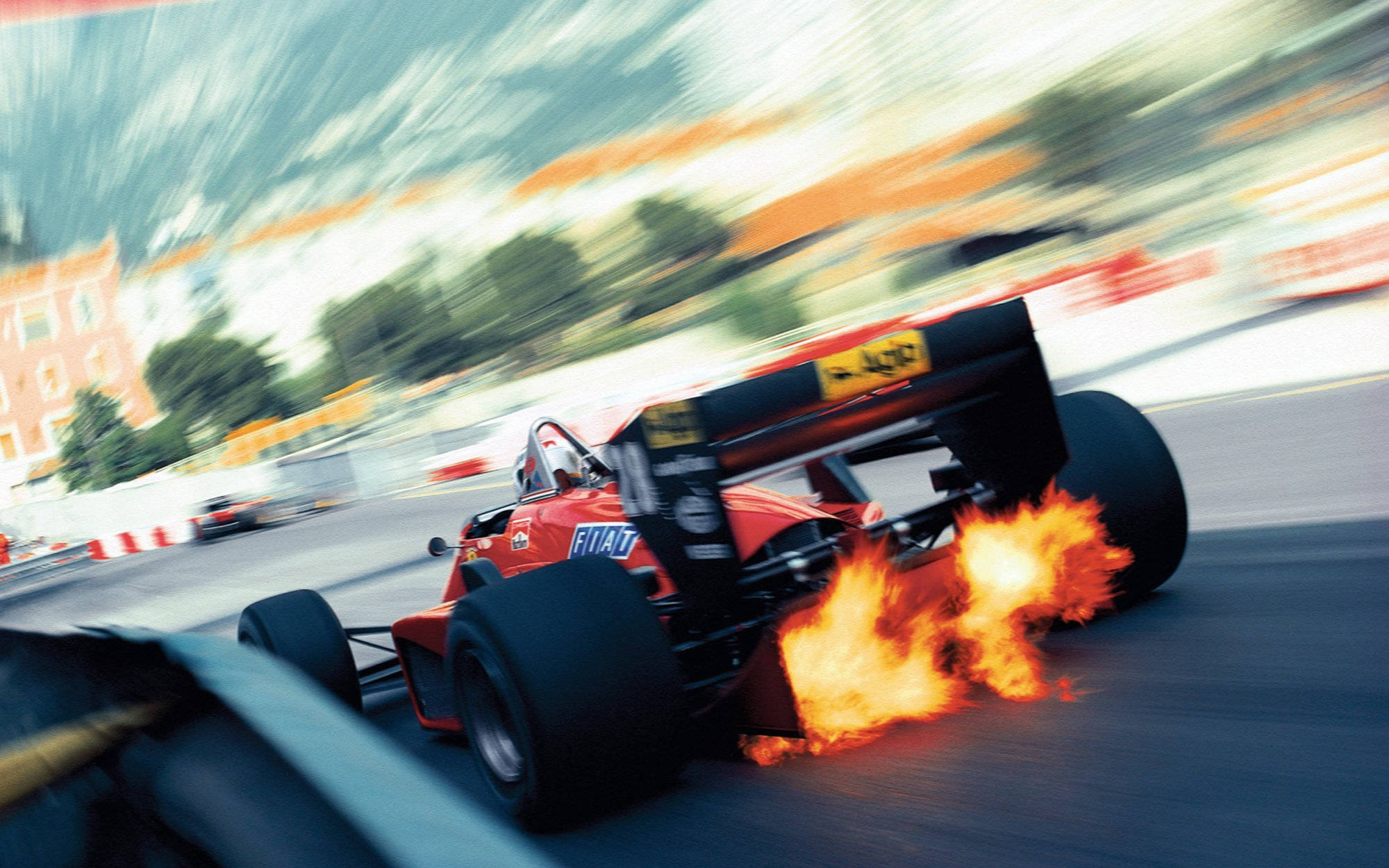 F1賽車桌面 - 排氣管噴火 壁紙 — 一輛紅色一級方程式賽車在賽道上飛馳，尾部噴出火焰，背景因動態模糊而呈現條紋效果。
