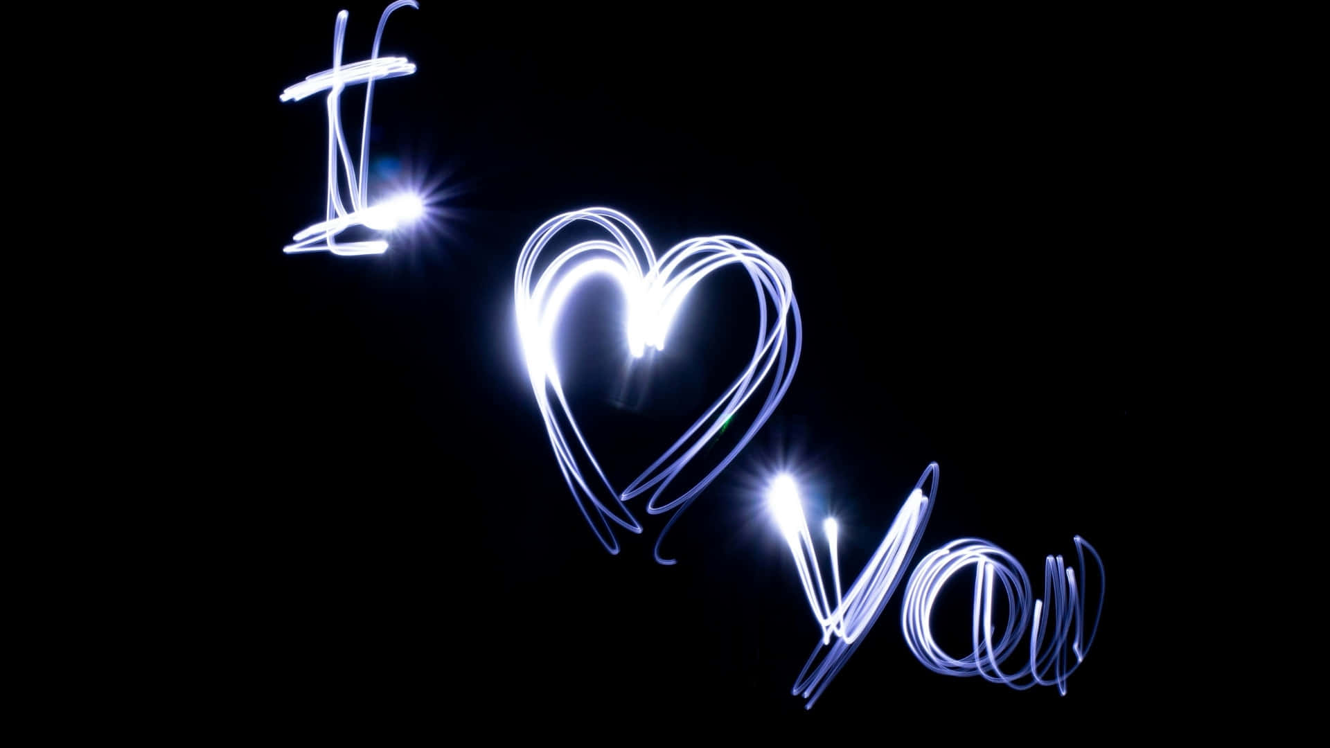  壁紙 — 發光的藍色光跡在漆黑的背景上拼出「I heart you」，並帶有明亮的鏡頭光暈。