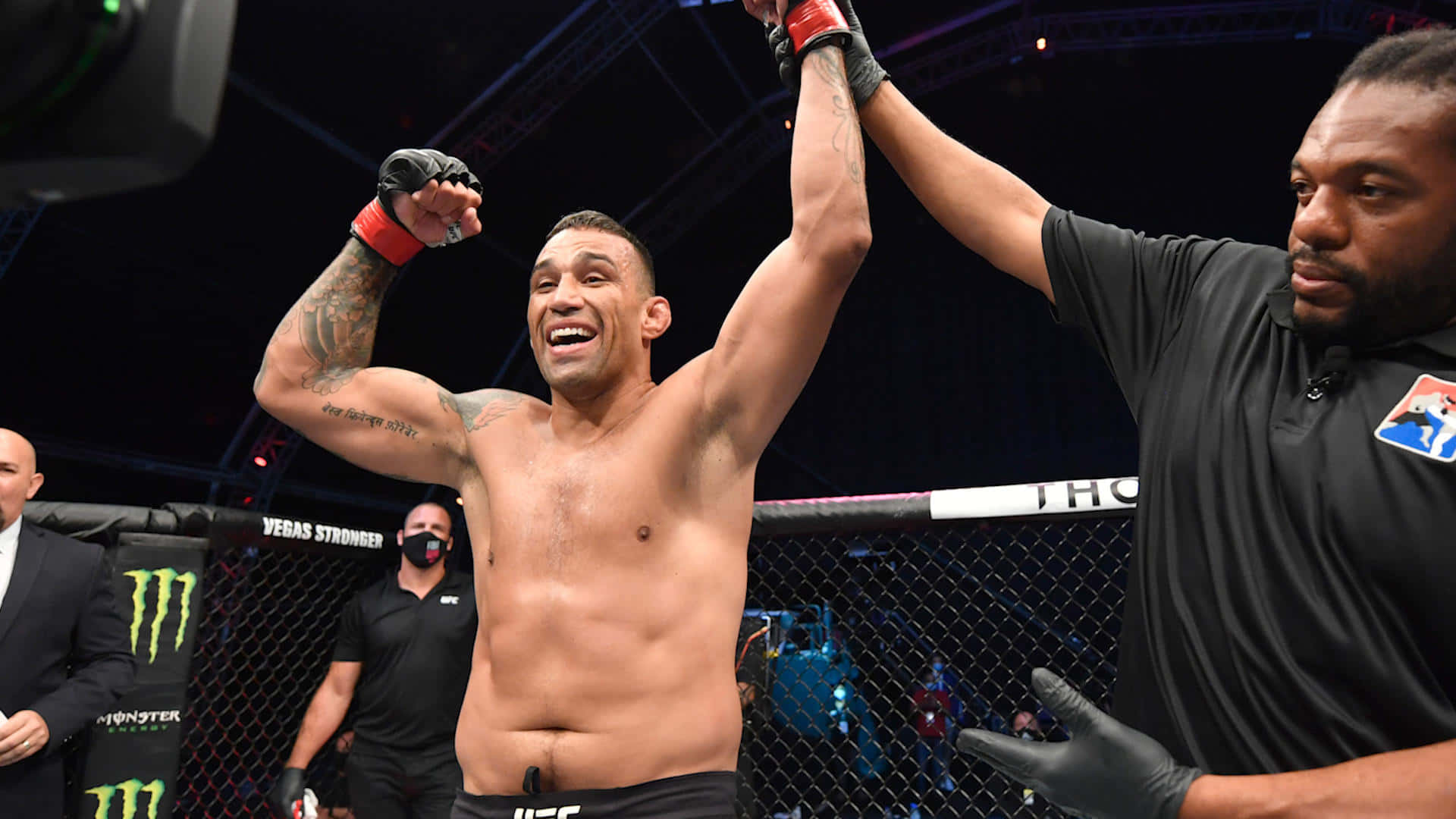 Fabricio Werdum 擊敗 Alexander Gustafsson 壁紙 — 一位勝利的MMA拳手在八角籠內慶祝，裁判在明亮的場館燈光下舉起他的手臂。