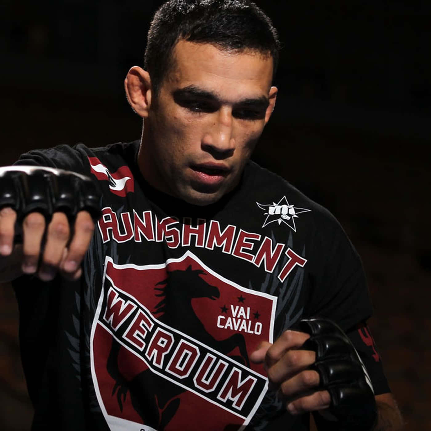 Fabricio Werdum 賽前準備 壁紙 — 一位專注的混合武術家，戴著黑色手套，身穿品牌襯衫，緊握拳頭向前，目光銳利。