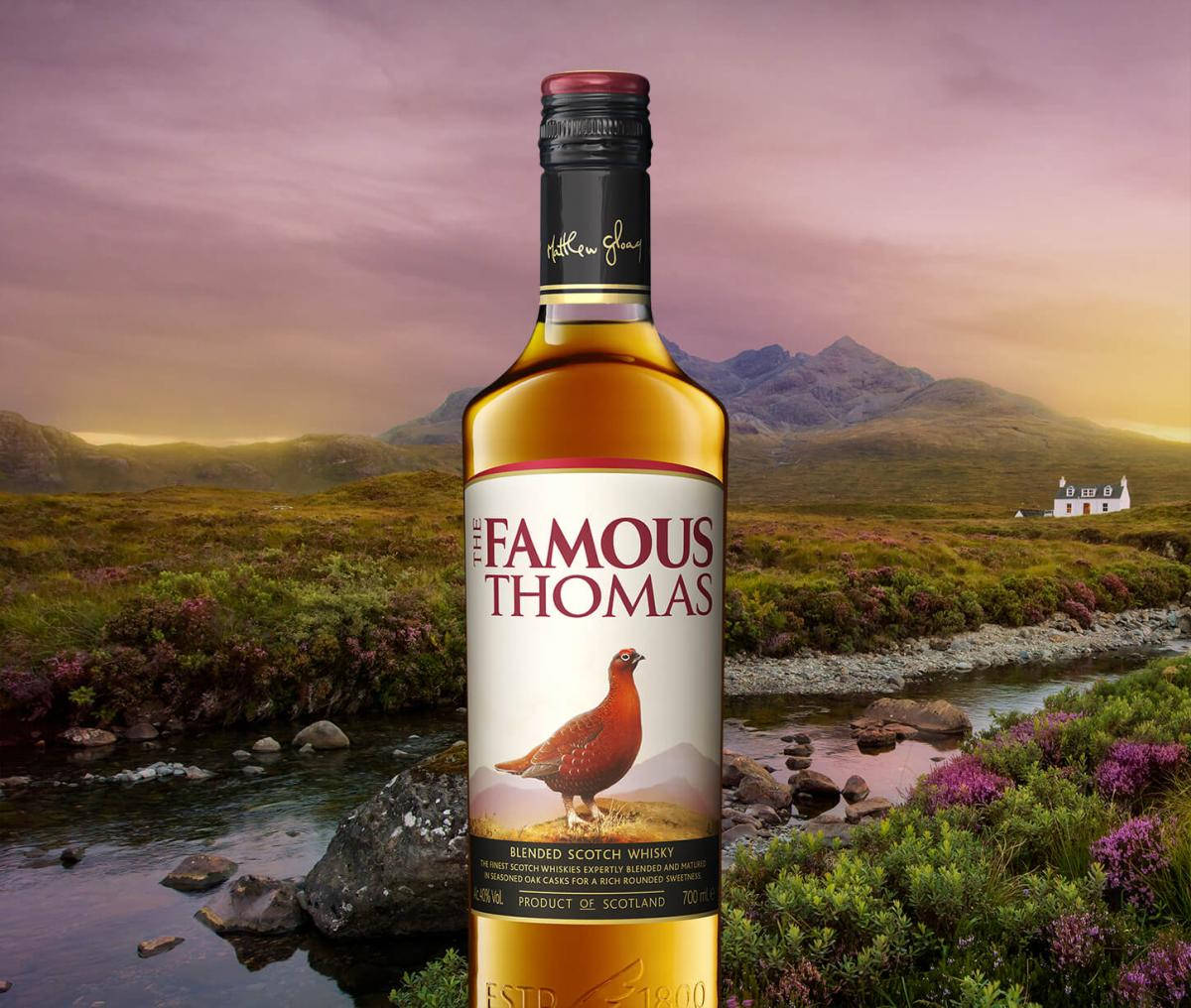 Famous Thomas威士忌酒瓶在蘇格蘭鄉村日落場景中，有山脈和紫色石楠花。