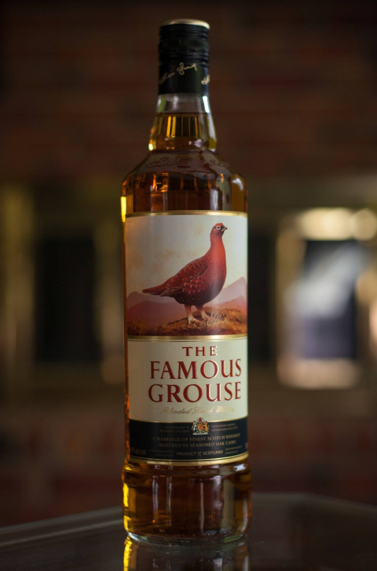 在昏暗環境中，反射表面上的 Famous Grouse 威士忌酒瓶。