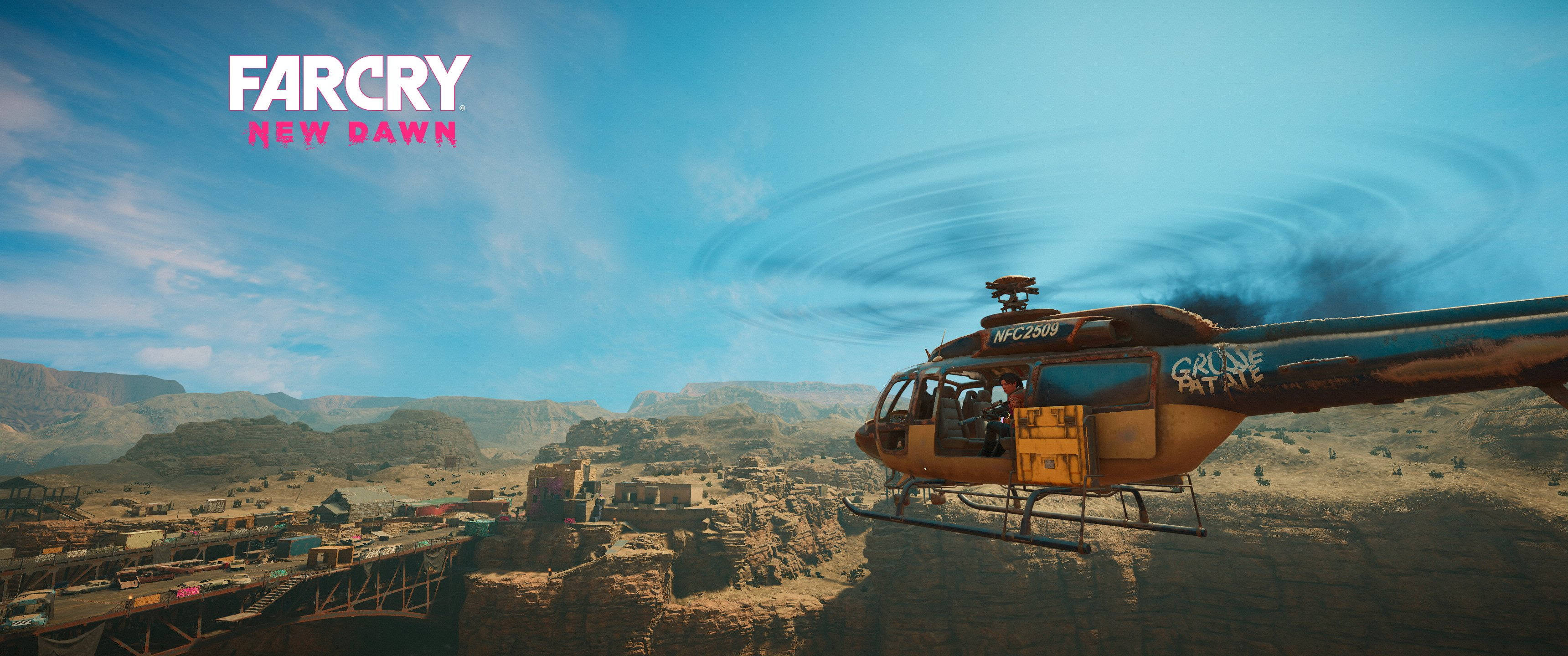 Far Cry New Dawn 直升機俯瞰 壁紙 — 一架歷經風霜的直升機盤旋在崎嶇的沙漠峽谷小鎮上空，天空湛藍，雲朵縹緲。