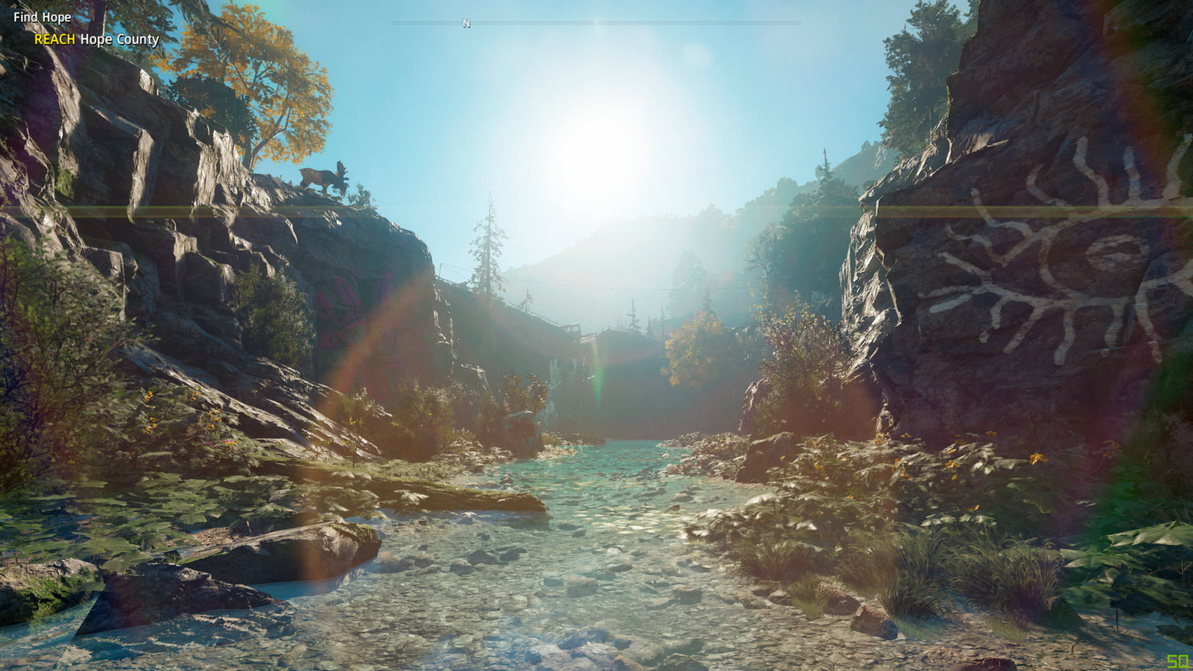 《Far Cry New Dawn》河山景觀 壁紙 — 陽光穿過岩石峽谷，照在清澈溪流上，懸崖上有古代岩刻。