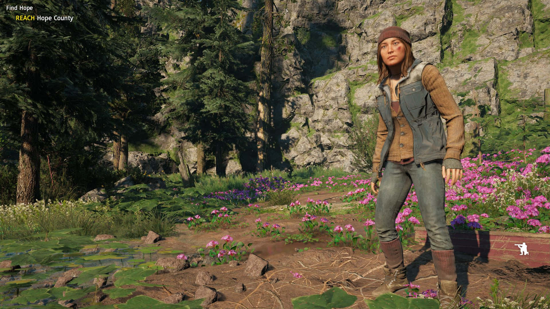 《Far Cry New Dawn》卡琳娜·賴1440p壁紙 壁紙 — 一位穿著堅固戶外裝備的女性，站在岩石懸崖邊，周圍是鮮豔的粉紅色野花和高聳的松樹。