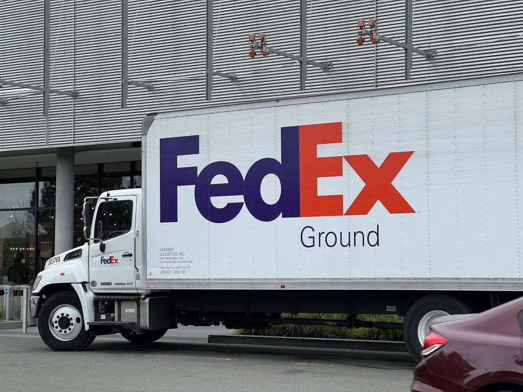 FedEx Ground送貨貨車停在一棟現代商業建築旁。
