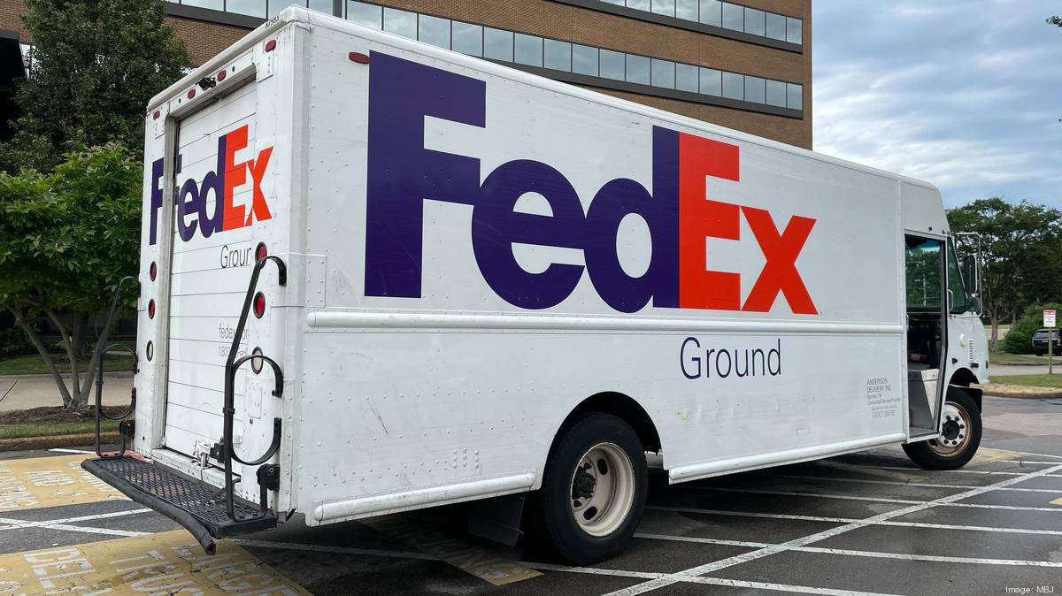 白色FedEx Ground送貨車停在靠近樹木和建築物的停車場。
